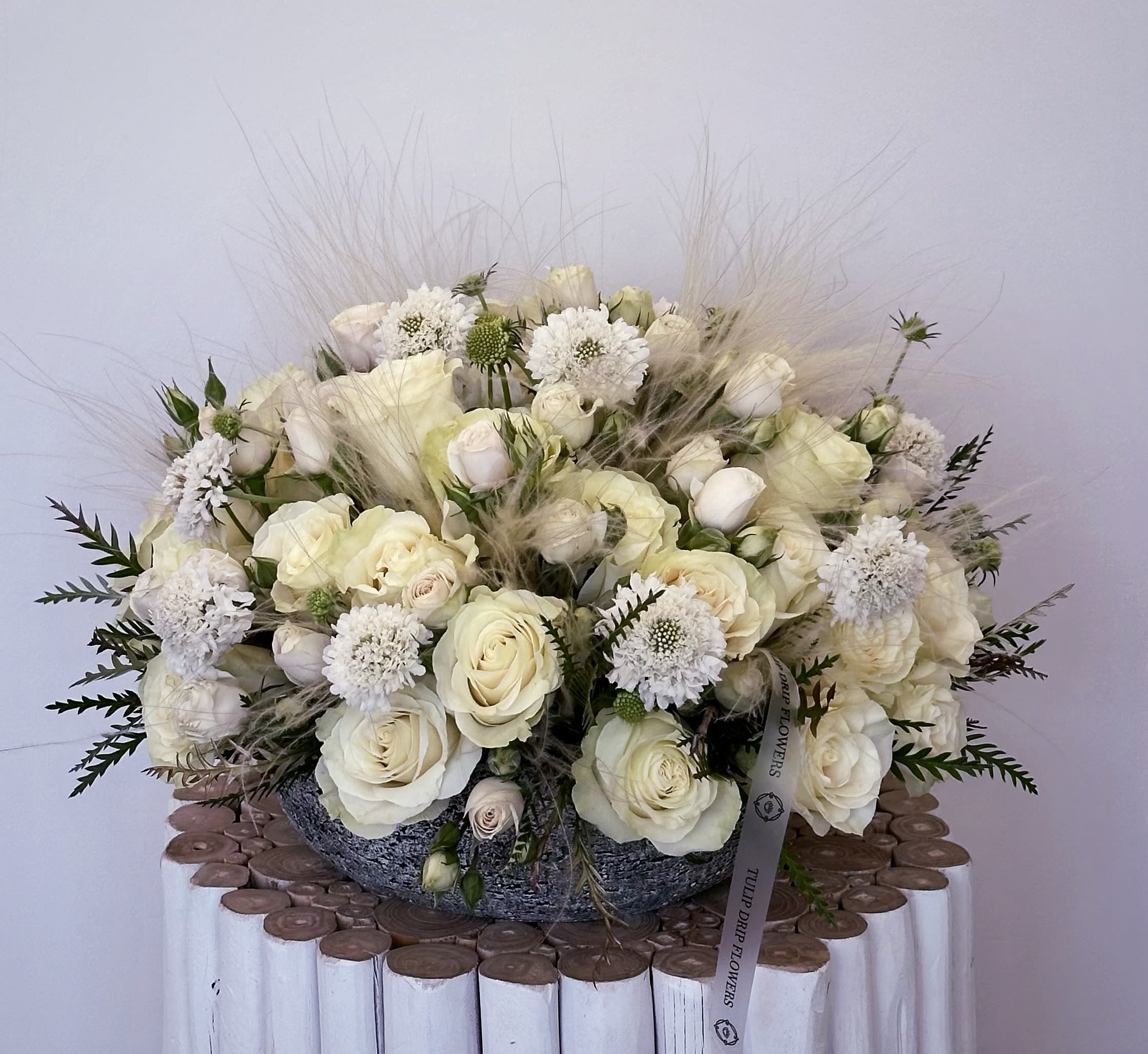 Elegant White Serenity Elegant White Serenity - The Elegant White Serenity arrangement features premium white roses, ranunculus, scabiosa, and soft greenery—perfect for weddings, sympathy, or elegant home décor. Styled in a luxury stone-textured vase, this bouquet radiates peace and sophistication. Ideal for sympathy gifts or all-white floral decor.