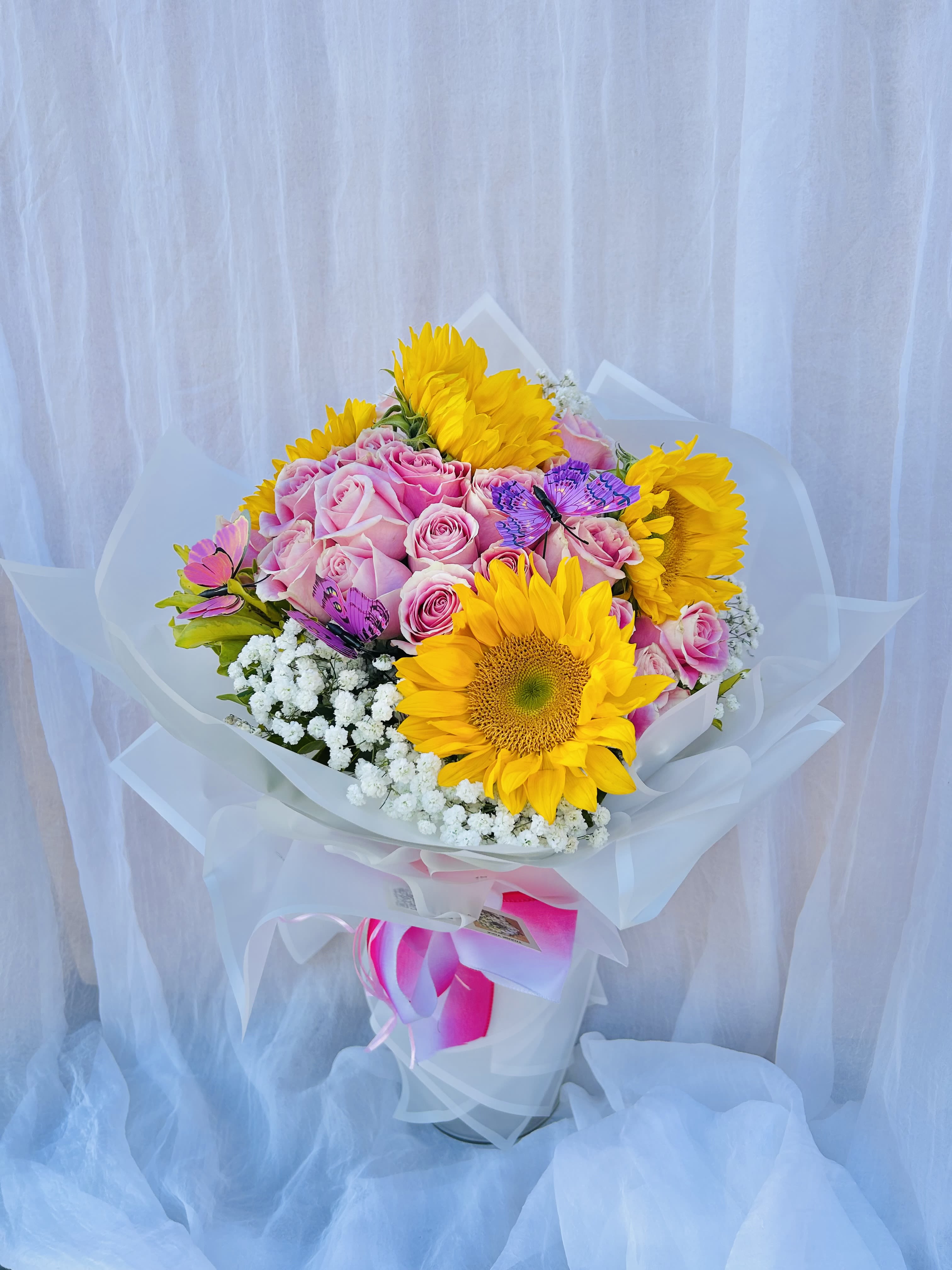 Sugar Blossom - Beautiful bouquet featuring sunflowers and pink roses with green accents, wrapped in white lining