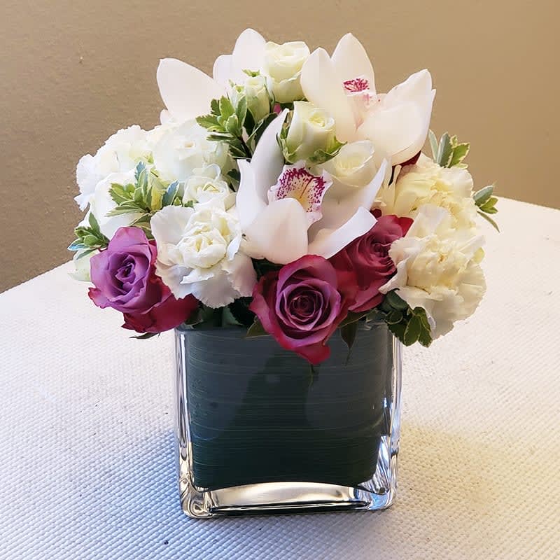 Cozy Blooms Bouquet - The Cozy Blooms Bouquet is arranged with roses, spray roses, hydrangeas, and carnations, then topped with classic cymbidium orchids.   This arrangement is a perfect expression of elegance and style, ideal for corporate gifting, as a thank-you gesture, or simply to add a touch of luxury to any space.   Approximately 10&quot; H x 9&quot; W. 