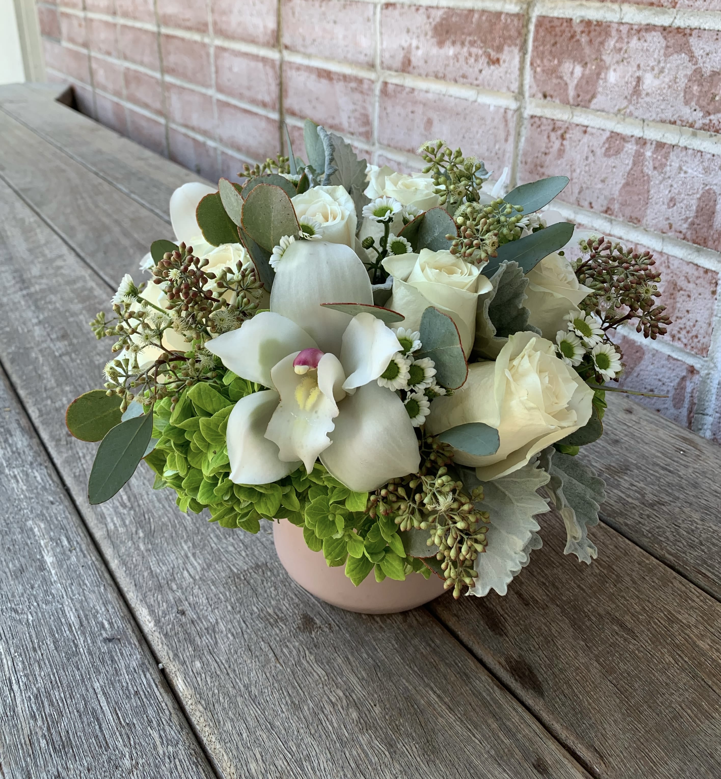 White Lotus White Lotus - a small arrangement of different greenary with white roses along with some cymbidium orchids