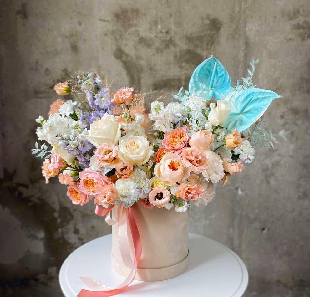 #50 Bliss Box - Light, dreamy, and bursting with feel-good color — the Bliss box is a celebration of pure joy. A radiant mix of soft peach, cream, blush, and lilac blooms, it’s made even more unforgettable with a pop of playful aqua.  This arrangement feels like happiness in floral form — perfect for birthdays, baby showers, housewarmings, or just because. Designed in a soft velvet box and finished with a flowing ribbon, Bliss brings color, comfort, and charm to every moment.  Seasonal flowers can be replaced with a similar one. Boxes and baskets can also be replaced with others.