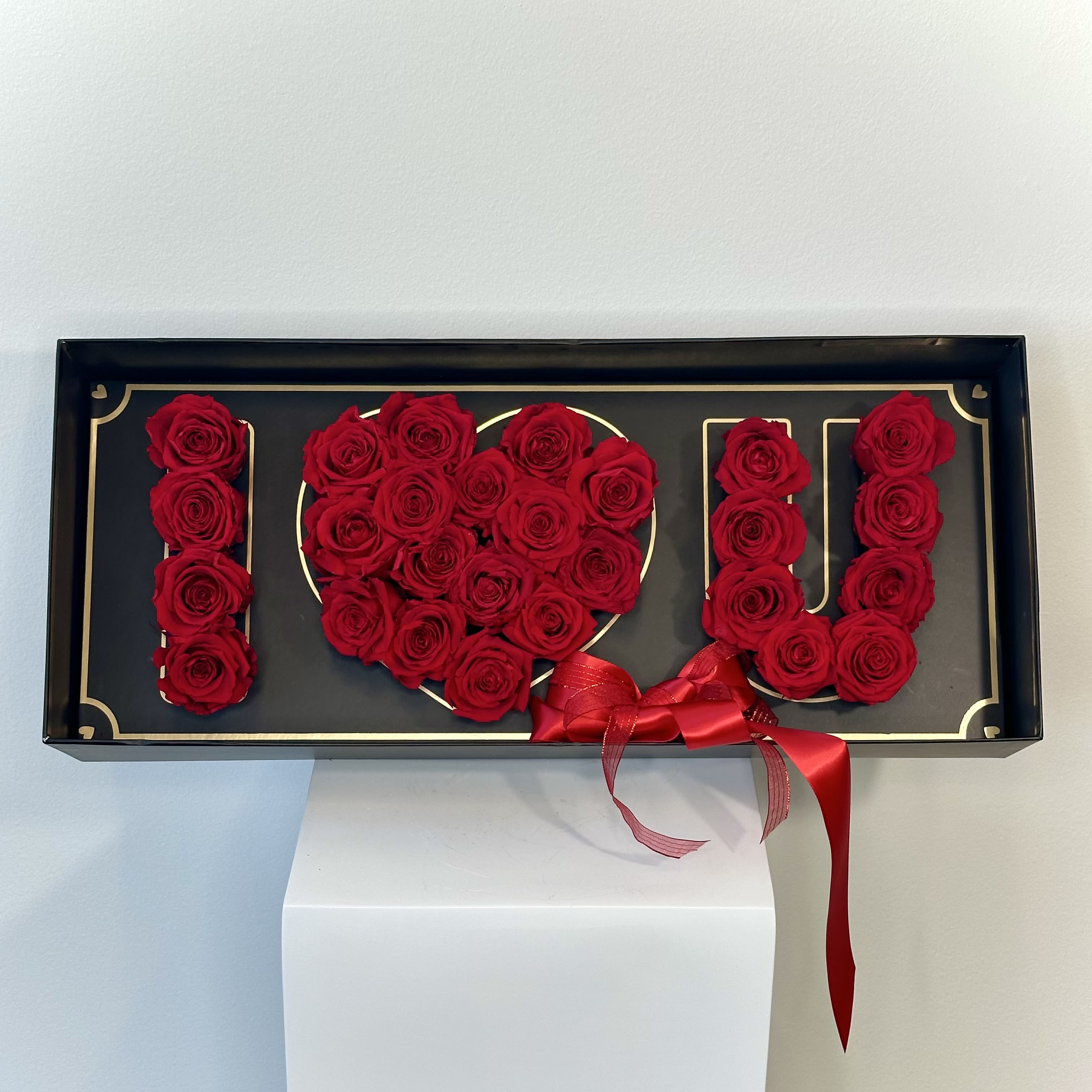 I Love U Preserved Roses Box - The &quot;I Love U Preserved Roses Box&quot; is a timeless declaration of affection, crafted with exquisite preserved roses that spell out &quot;I Love U&quot; in a stunning display. Each velvety rose, meticulously preserved to maintain its vibrant beauty, symbolizes a love that endures forever—just like the roses themselves, which remain radiant without fading. Nestled in a sleek, elegant box, these roses form a heartfelt message, their rich red petals tying in with a striking red bow for a nice, romantic effect. Perfect for anniversaries, proposals, or any moment where words alone aren't enough, this arrangement captures the essence of eternal devotion. The preserved roses require no maintenance, ensuring your gesture of love remains as vibrant as the day it was given. This luxurious gift blends sophistication and sentiment, offering a lasting testament to your affection that will be cherished for years to come. Please keep in mind to avoid prolonged exposure to direct sunlight and high humidity and do not water or place the roses in water. Avoid direct contact with hands or clothing as it may stain.