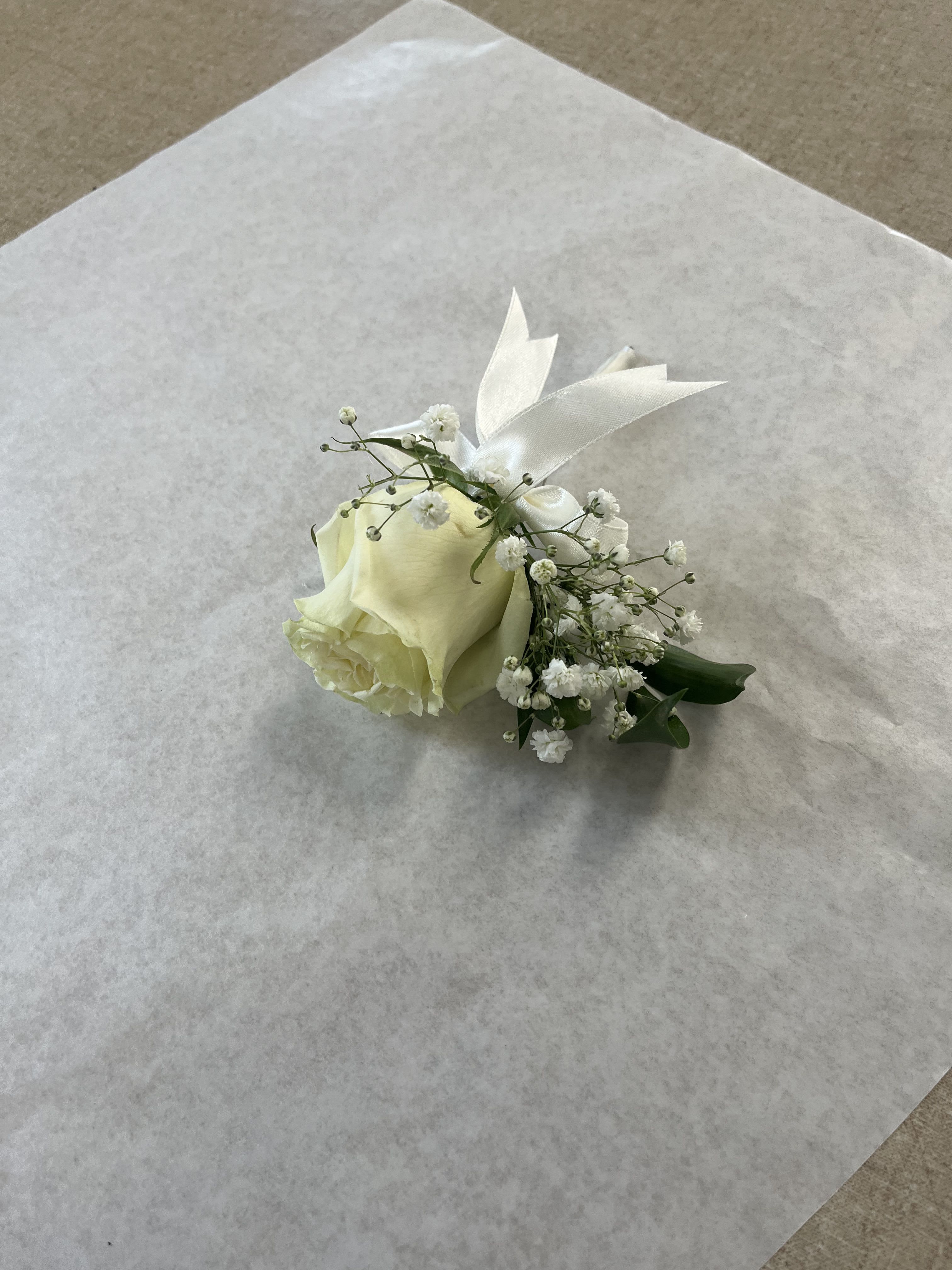White Boutonniere White Boutonniere - It will depend on the roses in stock Mini Rose white, green leaves, and gypsum.