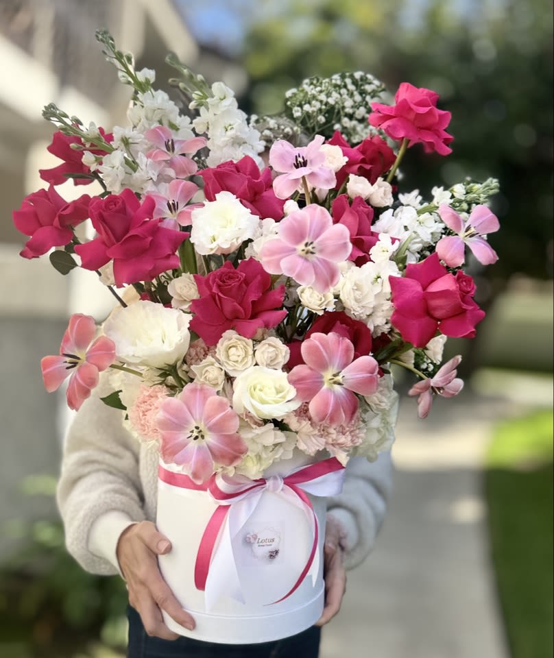 Pink Elegance Flower Box  - A true showstopper, this floral composition bursts with charm, romance, and grace. Designed in a crisp white hatbox and tied with matching pink and white satin ribbons, the arrangement features an exquisite blend of fuchsia roses, soft pink tulips, white lisianthus, carnations, and delicate accent flowers. The color palette is both bold and elegant, making this arrangement perfect for celebrations and unforgettable moments.    With its airy structure and luxurious height, this flower box is ideal as a centerpiece for a bridal shower, engagement party, or elegant birthday celebration. The romantic mix of pinks and whites makes it an excellent gift for a girlfriend, wife, mother, or best friend – someone you want to surprise with beauty and warmth.    Perfect for flower delivery in Los Angeles, this arrangement offers a modern twist on traditional floristry. It's not just flowers in a box – it's an experience wrapped in color and elegance.