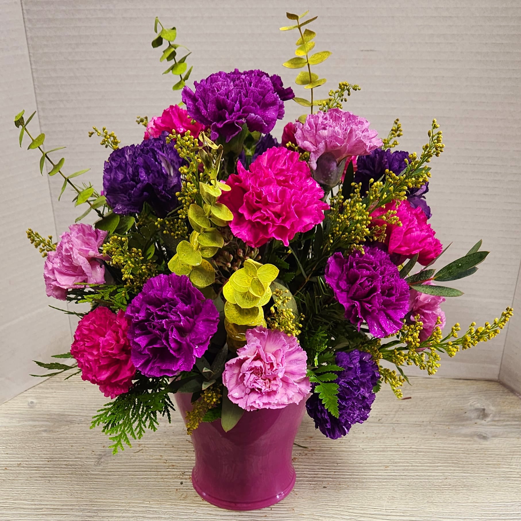 Purple Punch - A spectacular mix of carnations in varying shades of purples and hot pinks with greens and tinted eucalyptus in a matching purple container. Sure to make your &quot;purple&quot; lover LOVE you!
