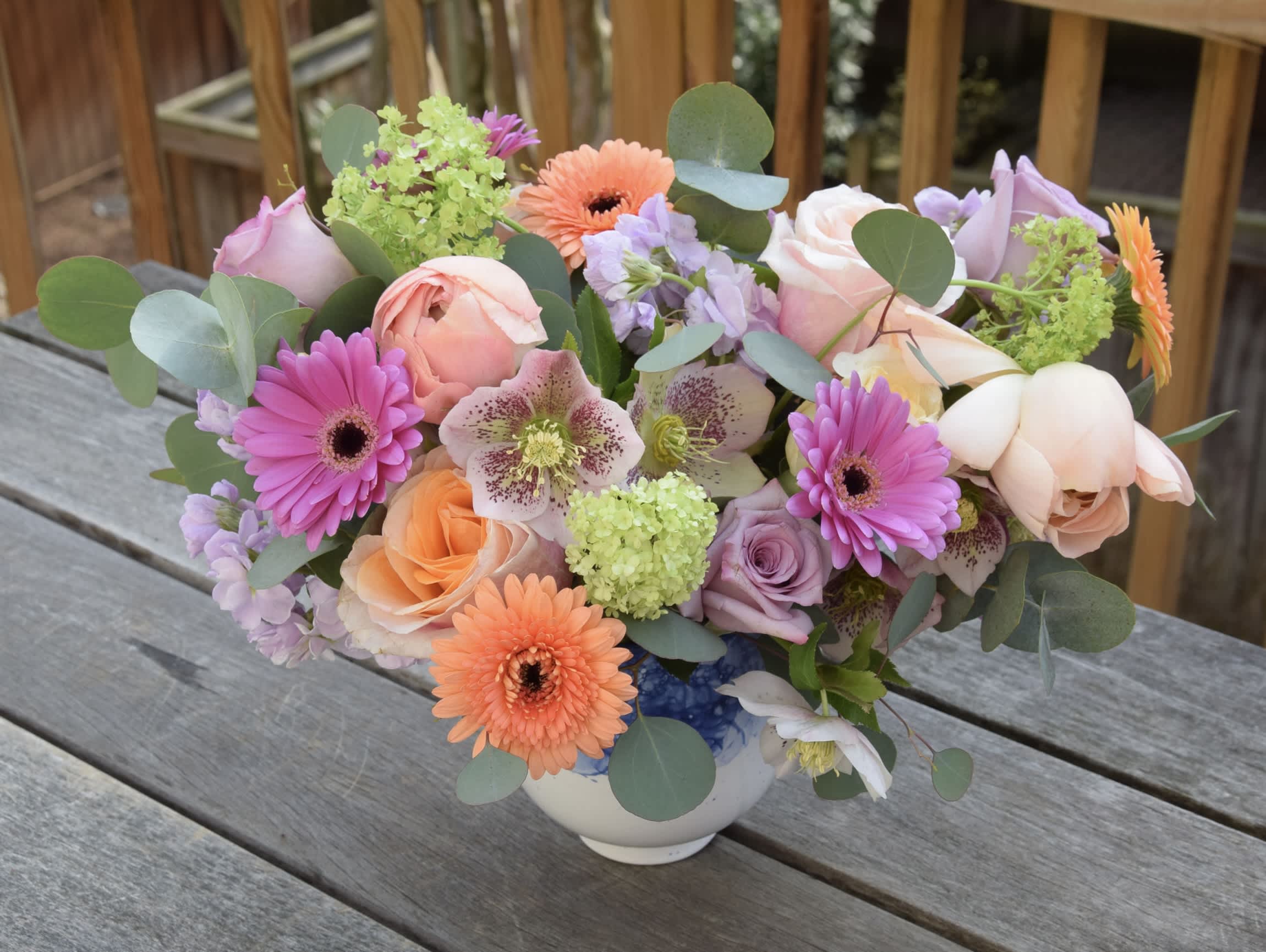 Spring Is In the Air Spring Is In the Air - A lovely flower arrangement with premium flowers and spring blooms like tulips, hellebore and viburnum in Accent Decor white-blue vase. Flower selection may vary but always roses, gerber daisies, stock, ranunculus, lisianthus and tulips.