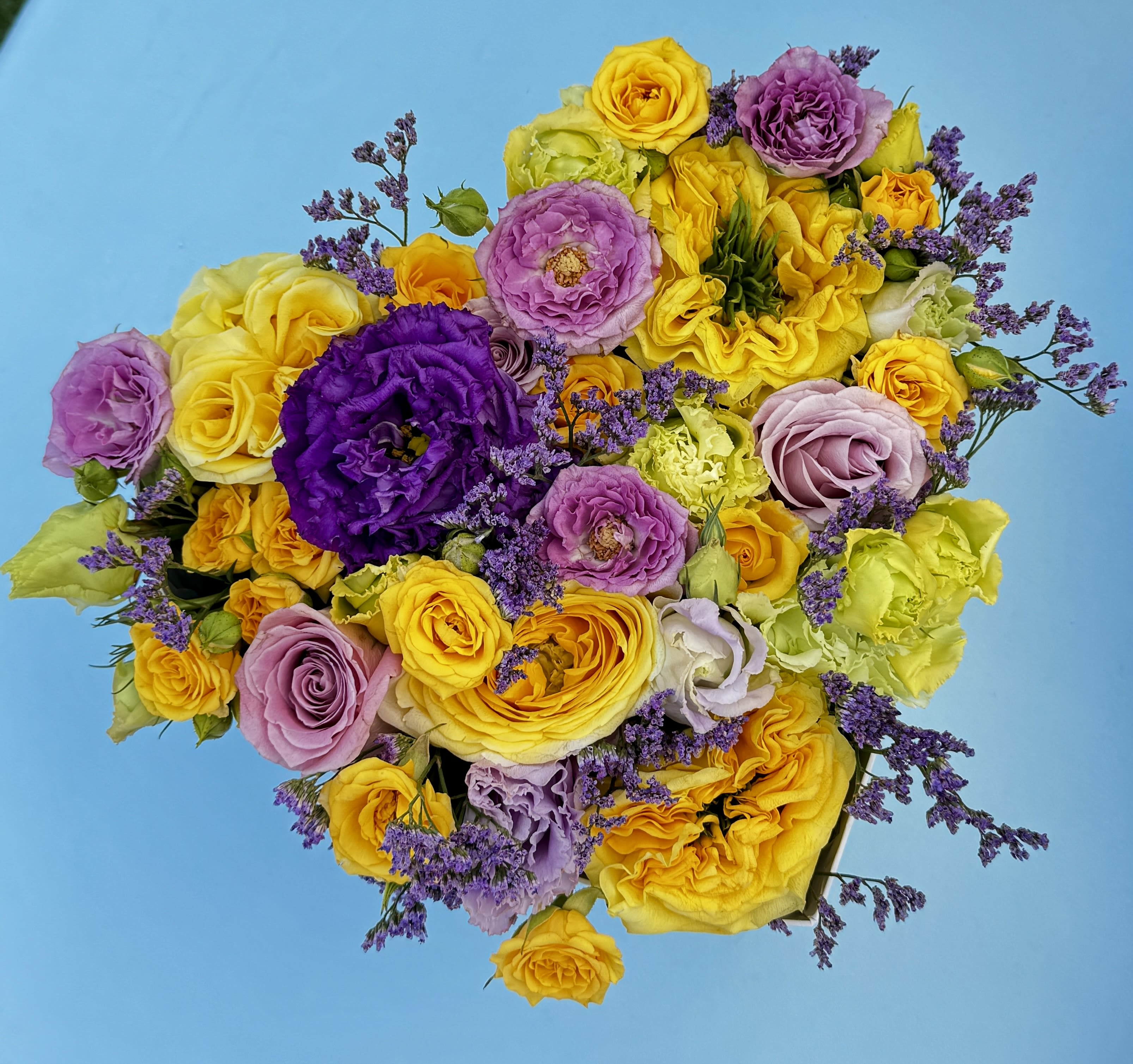 Golden Violet Box - A bold fusion of color and elegance, Golden Violet is a celebration of contrast and harmony. This radiant arrangement blends buttery yellow ranunculus, lavender and lilac roses, bright golden roses, lush lisianthus, and accents of delicate purple statice. The palette is both regal and joyful — evoking sunshine, creativity, and refined beauty.  Perfect for statement gifting, luxury events, or simply elevating your space with artistic flair.  Style: Vibrant, expressive, modern-luxury Fragrance: Softly floral and fresh