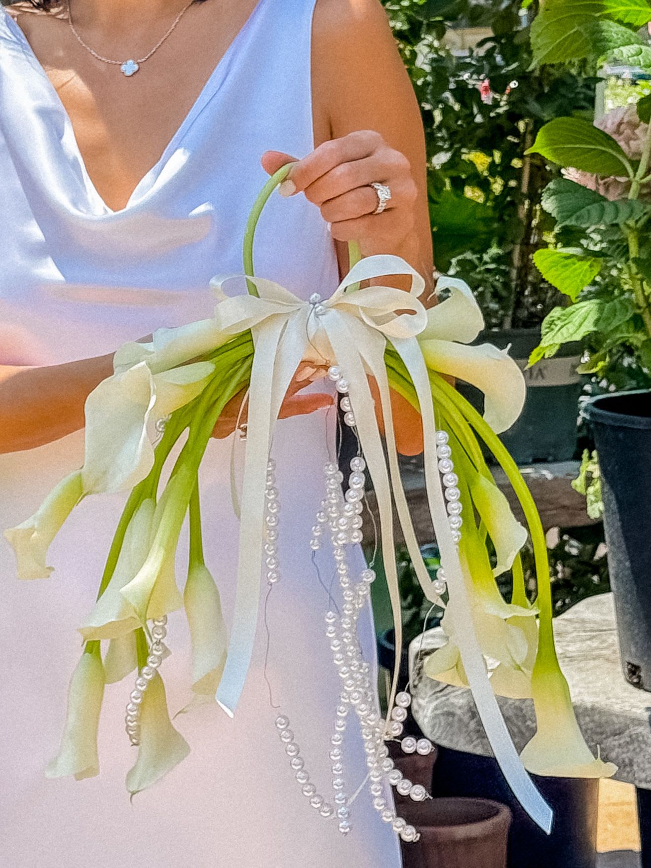 Lover Loop  - Lover Loop isn’t just a bouquet — it’s a whole vibe. Think modern goddess energy with vintage bridal glam. She loops love around her wrist and lets the world know she’s not just walking down the aisle — she’s floating. With cascading pearl strands, creamy calla lilies, and soft ivory ribbons, this floral handbag hits different. Elegant, extra, and a lil’ unexpected — just like your forever love.  Size: H19” W22” L4” Weight 0.80lb 