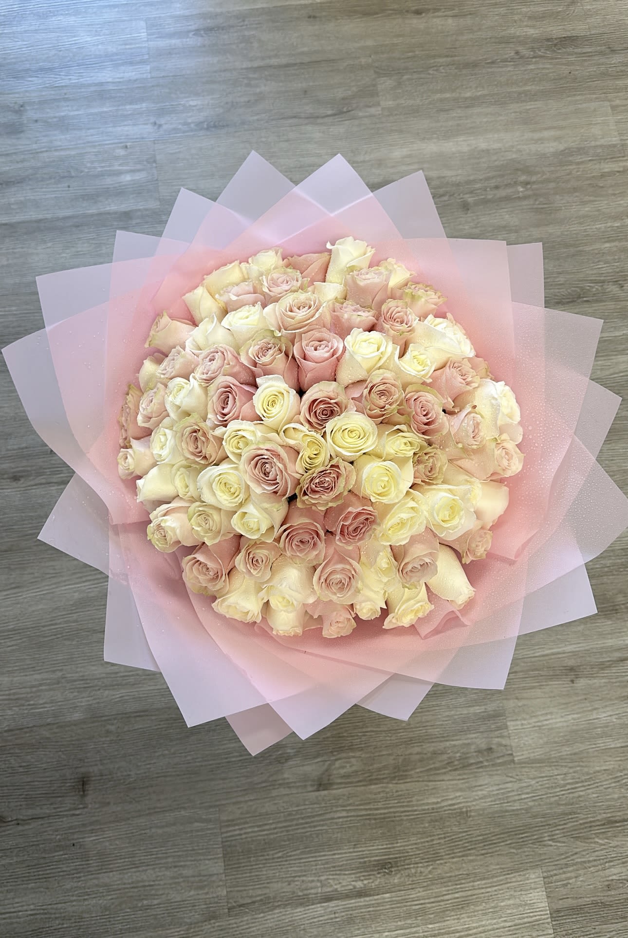 Blushing Petals - Delight in the soft, romantic beauty of our &quot;Blushing Petals&quot; bouquet. This charming arrangement features a delicate mix of white and pink roses, elegantly wrapped in pink paper. Perfect for any occasion, this bouquet brings a touch of grace and sweetness to your sentiments. Please note, a vase is not included, allowing you the freedom to display these lovely blooms in your favorite vase at home. 