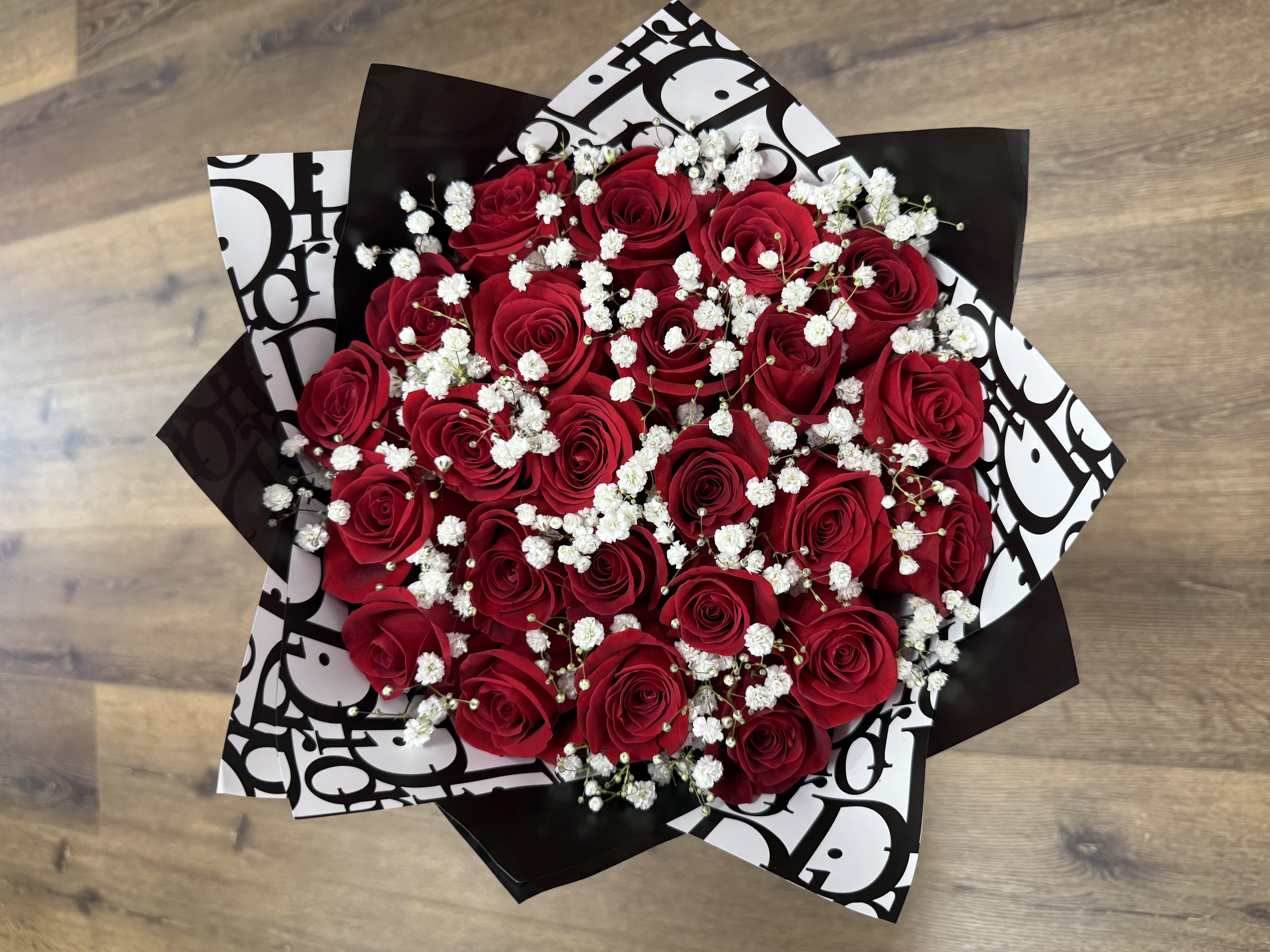 Midnight Chic - A bold statement of timeless elegance, the Midnight Chic bouquet features rich red roses framed by crisp, couture-inspired wrapping and a delicate veil of baby's breath. Perfect for making a lasting impression, this design exudes sophistication with a hint of drama.