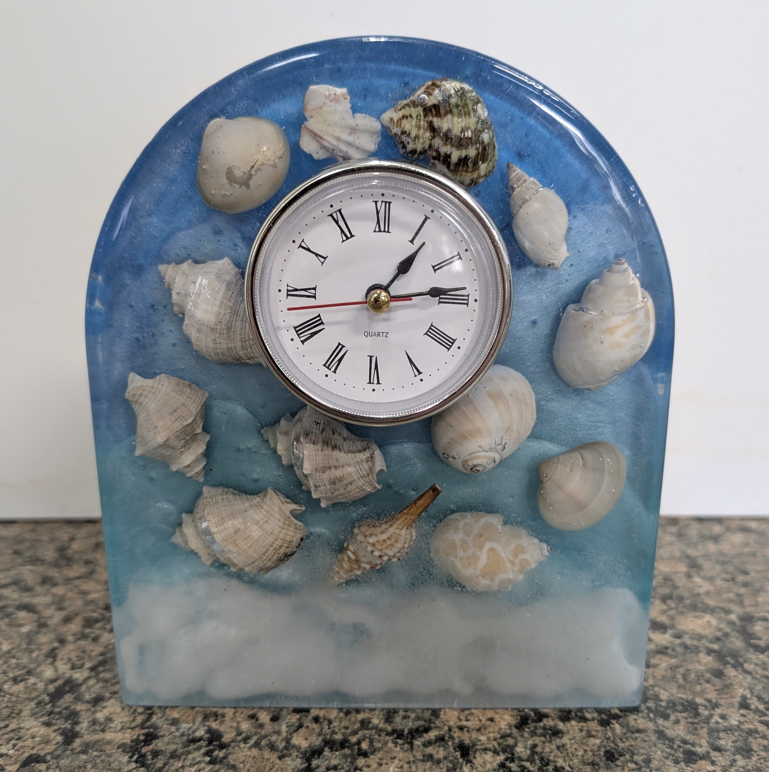Ocean Clock Ocean Clock - This in house made resin clock is a great addition to any home. It is 7 inches tall, 6 inches wide and 1.5 inches deep. Its is solid resin with glistening mica powder for colorants, so it does have some weight to it to keep it self standing. The clock is powered by 1 AAA battery.