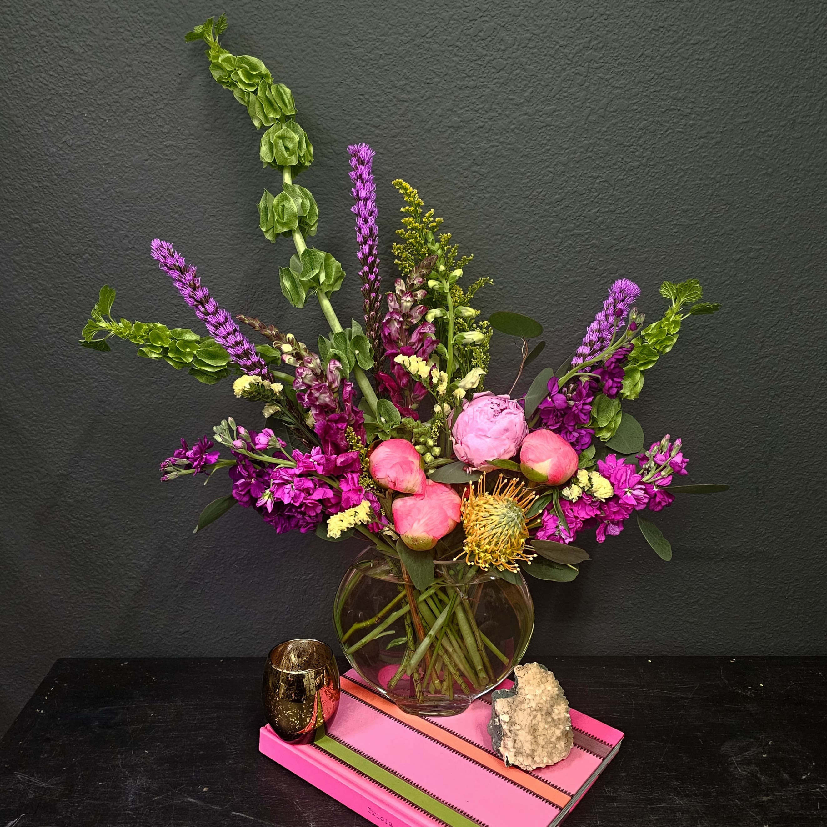 Jewel Opulence - Indulge in the ultimate luxury with our Opulent Jewel-Toned Flower Arrangement. This tall and modern design features a stunning mix of vibrant peonies, exotic orchids, tropical blooms, and lush roses, all complemented by an array of rich greenery. The striking jewel tones—deep purples, radiant reds, and vibrant pinks—create a luxurious and eye-catching display that will elevate any occasion. Ideal for those who appreciate sophistication, this arrangement adds an air of elegance and class to your home, office, or special event.  Perfect for birthdays, anniversaries, corporate events, or simply to impress, this arrangement is a true statement piece. Delivered with care and attention to detail, our flower delivery service covers Denver, Greenwood Village, DTC, Cherry Creek, and Cherry Hills, ensuring your arrangement arrives fresh and beautifully presented.  Order the Opulent Jewel-Toned Flower Arrangement today and experience the luxury and beauty of expertly curated floral design.