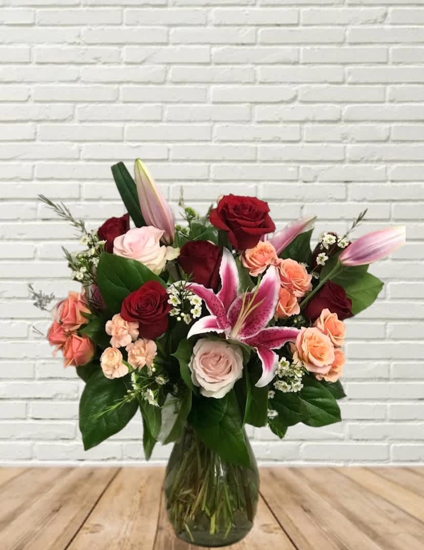 Love Song Love Song - A grand style arrangement in true red & pink tones! Seasonal floral mix with focal lilies and roses.