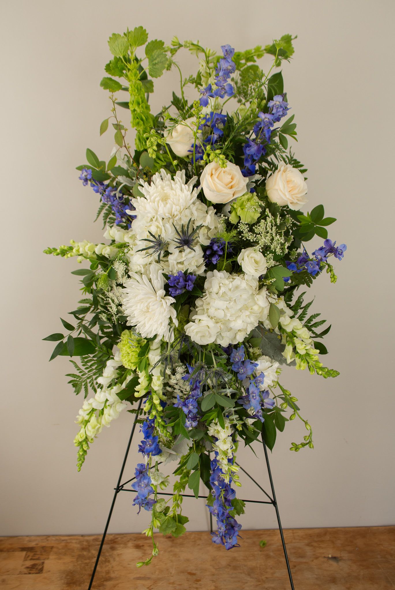 Blue Traditions Spray - A traditional sympathy spray with accents of blue and white.  Varying amounts of blue flowers can be added. 