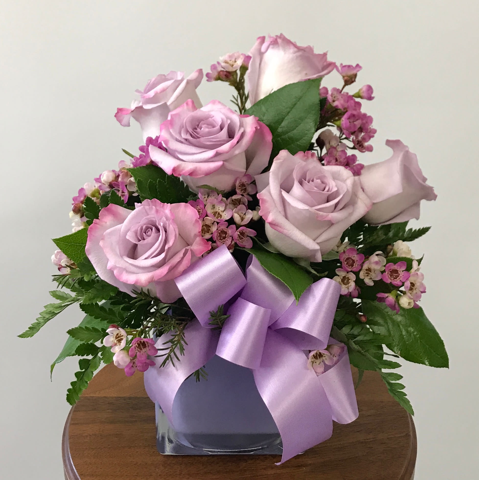 Morning Melody Morning Melody - Shades of purple are in perfect harmony in this pretty arrangement. A lovely bouquet that's sure to make someone's day! Cube color may vary. Lavender roses and waxflower, or other filler, with greenery are hand-delivered in a cube that's accented with a purple ribbon.