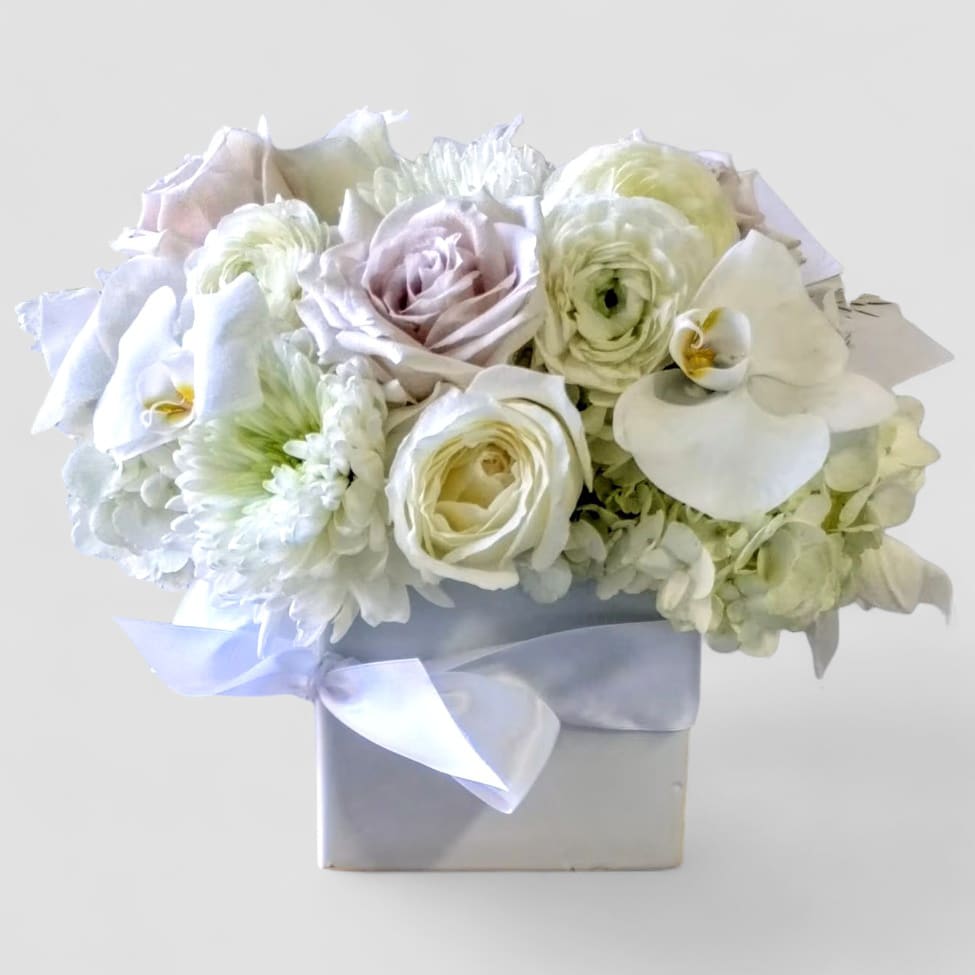 Condolences White Bouquet Designer's Choice - White blossoms roses orchids and more arranged in a beautiful white glass modern cube style vase. Perfect to send as a condolences and to show them how much you care. All of my designs are always made extra special and unique each and every time. Send them you deepest condolences. 