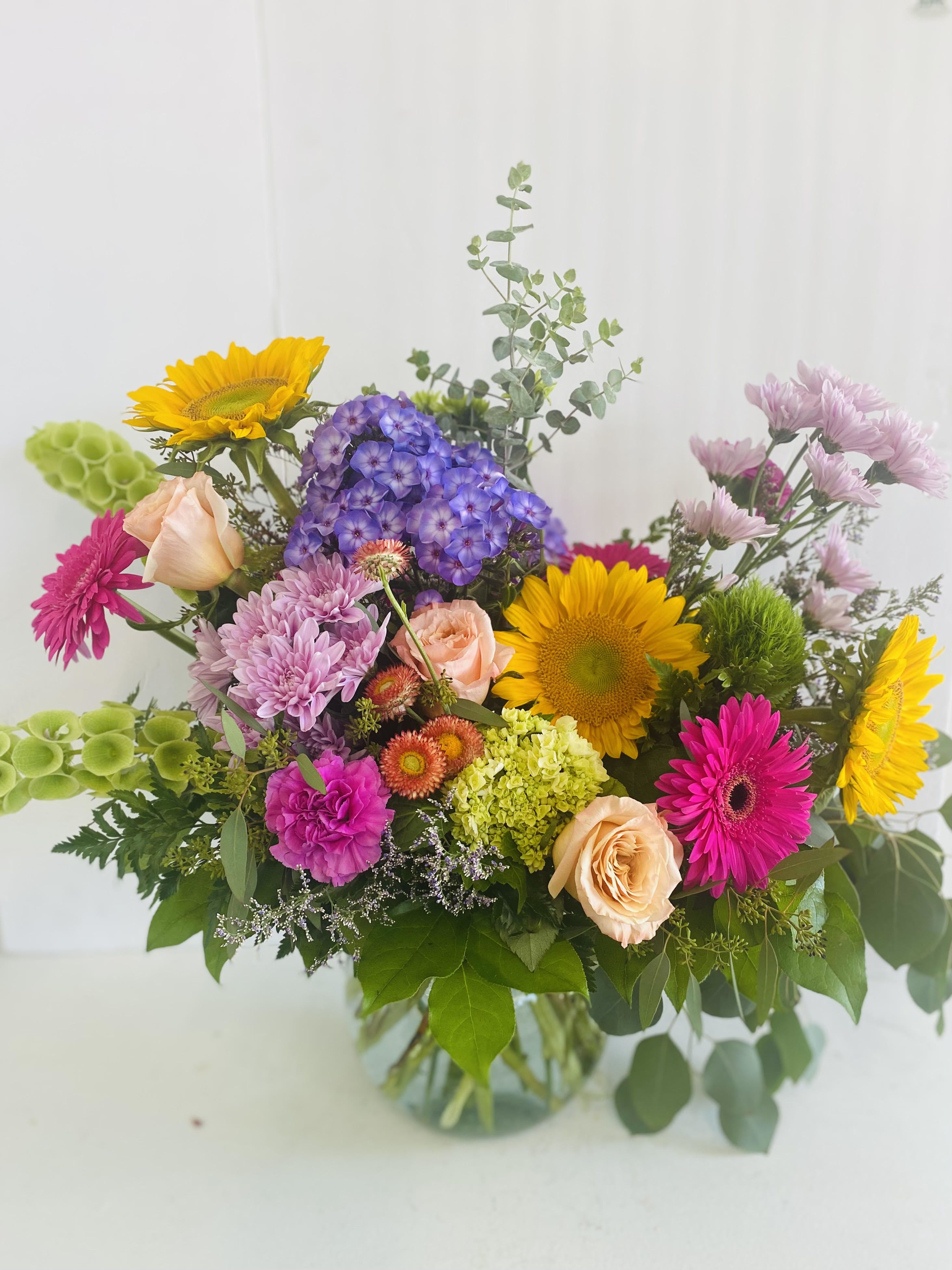 Bloomscape Bloomscape - This playful and vibrant arrangement is full of charm, featuring bold orange and hot pink gerbera daisies, magenta carnations, soft pink spray roses, and vivid green trick dianthus. Accented with deep greenery and whimsical fillers, all styled in a glass vase, it’s a fun and lively design perfect for brightening someone’s day.