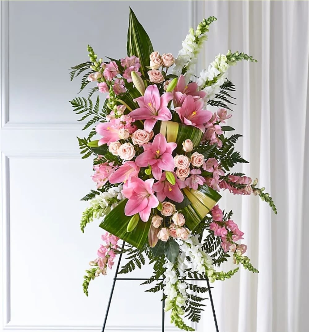 Elegant Embrace Standing Spray - Our Elegant Embrace Standing Spray shares the warmth and comfort your loved ones need during this difficult time through each blushing bloom. A local florist beautifully combines lilies, spray roses and snapdragons with greens to express your heartfelt love.