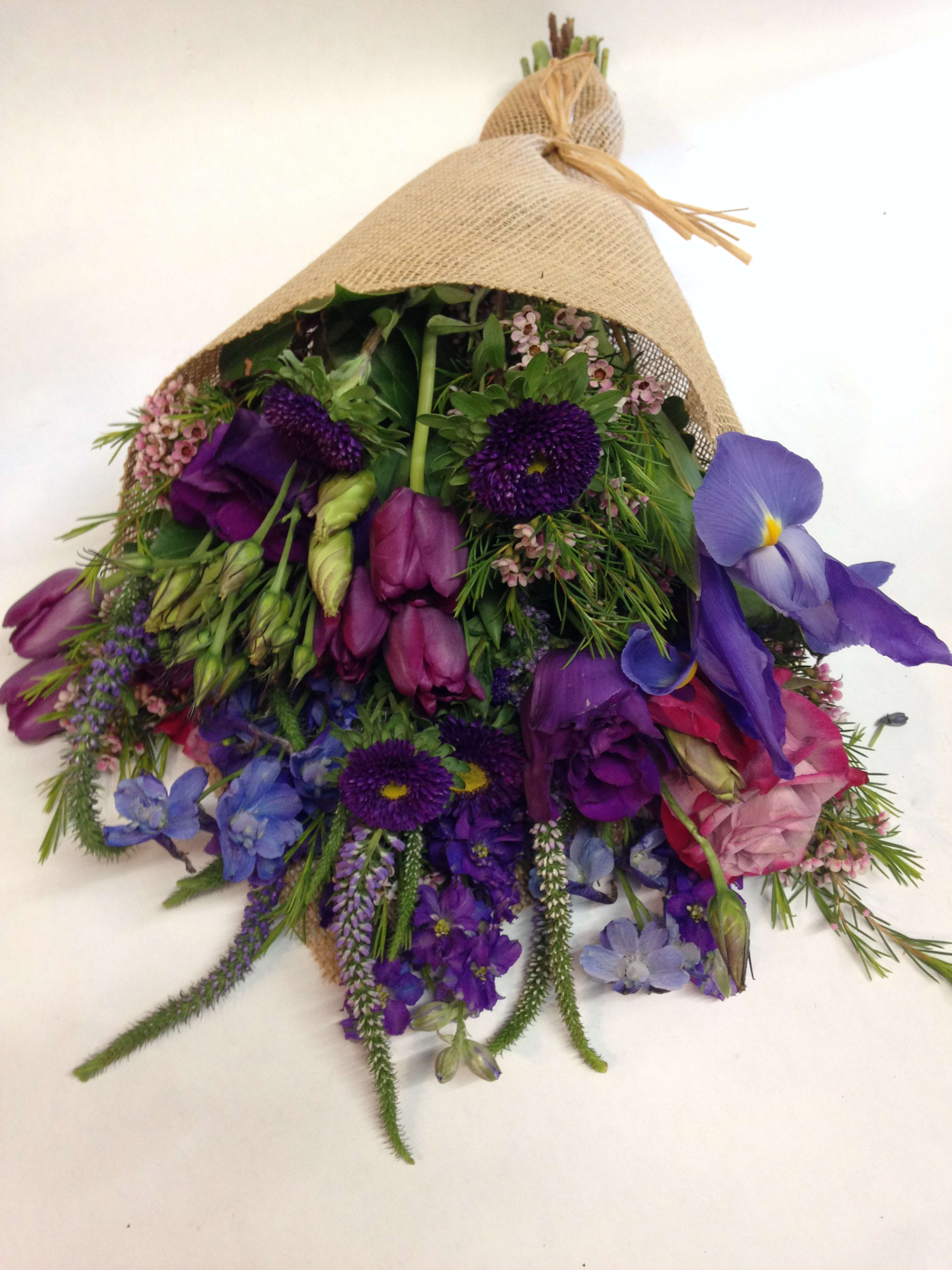 The Violet Femme The Violet Femme - This burlap wrapped bouquet comes complete with varying shades of violet, lavender, and blue. Flowers in the featured arrangement are: aster, tulip, iris, veronica, lisianthus, rose, belladonna delphinium, etc. (Some flowers may be subject to change depending on the season. We will contact you with available flower substitutions; please contact us with specific questions if you are concerned with flower availability, thanks!) Featured arrangement: $100.00 (Regular Price)
