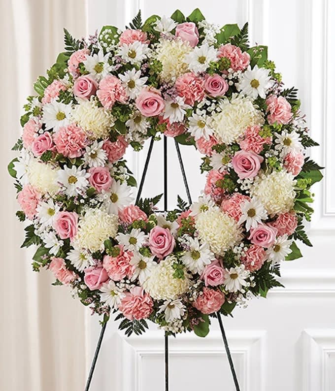 Pink &amp; White Standing Wreath Standard - Florist of Omaha - Celebrate a life with this Pink and White Standing Wreath. The wreath is created by one of our local florist partners near you with pink roses, pink and carnations, white mums, greenery and more. All the flowers are arranged in a wreath shape, a beautiful gift for a funeral. The deluxe wreath measures approximately 34&quot;H x 34&quot;W without easel and the regular is approximately 30&quot;H x 30&quot;W without easel. The Easel will be delivered with the Pink Sympathy Funeral Wreath, along with a card message.   Includes:  • Pink Roses  • Pink Carnations  • White Mums  • White Daisies  • Baby's Breath