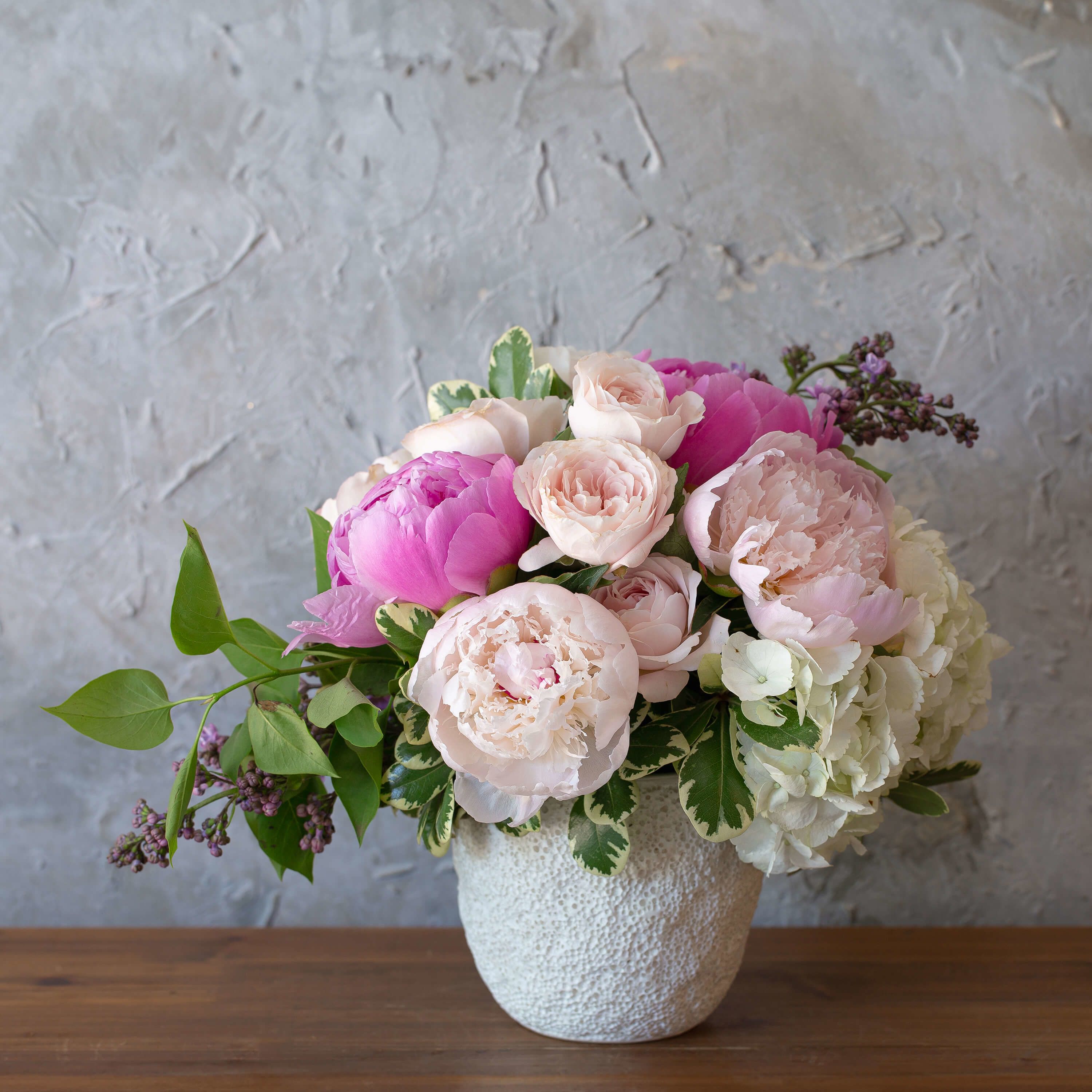Pampered Peony Pampered Peony - Fresh blooms to pamper your love. Pampered Peony is an perfect mix of flowers like peonies, hydrangeas and lilac to make a true masterpiece.