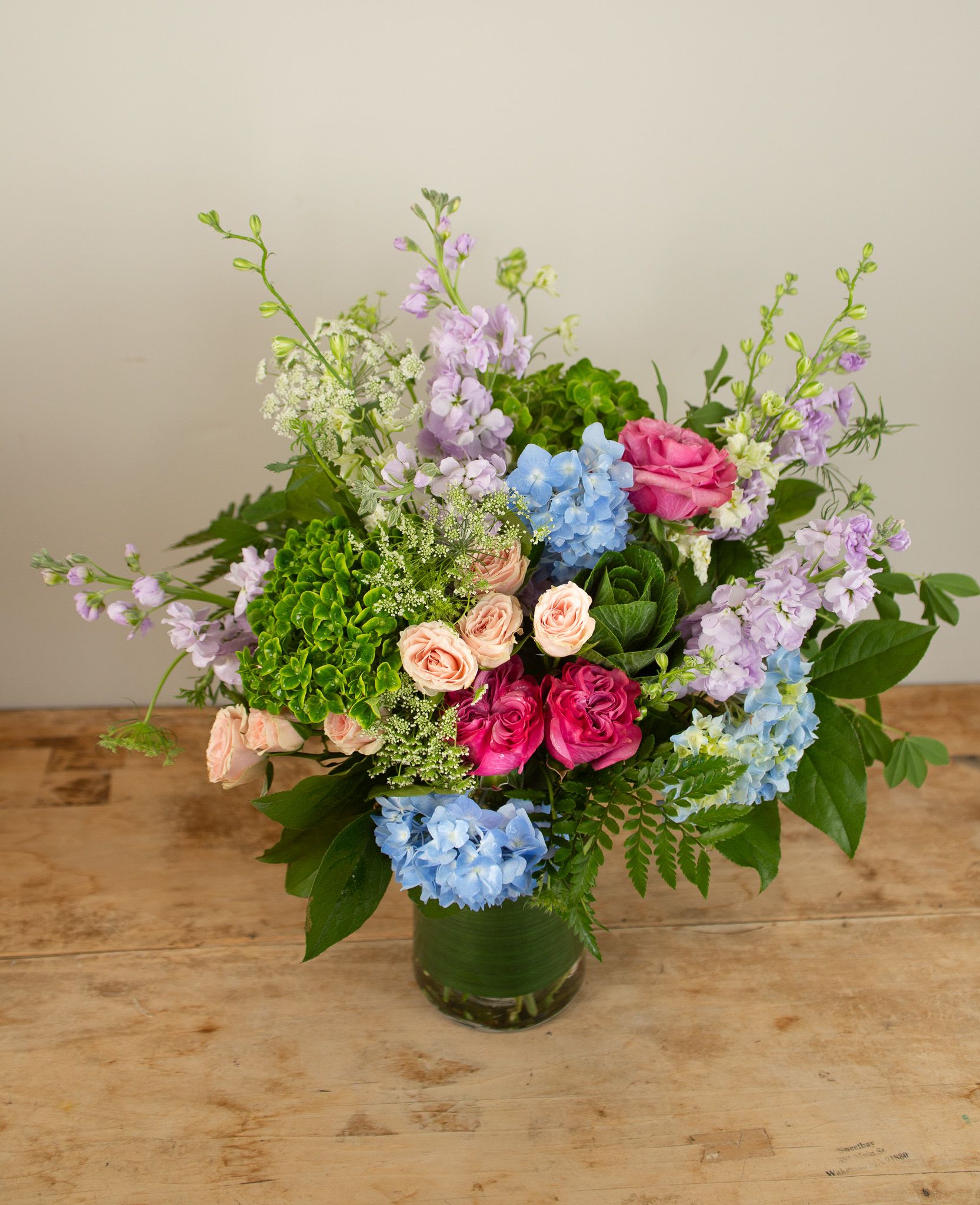 Cottage Gathering - Invoke fond memories of fragrant walks in the garden with this lush arrangement. Stems include hydrangea, garden roses, and delphinium amongst other spring favorites. This arrangement is sure to make any one in your life feel treasured.   Approx 15&quot;x15&quot;