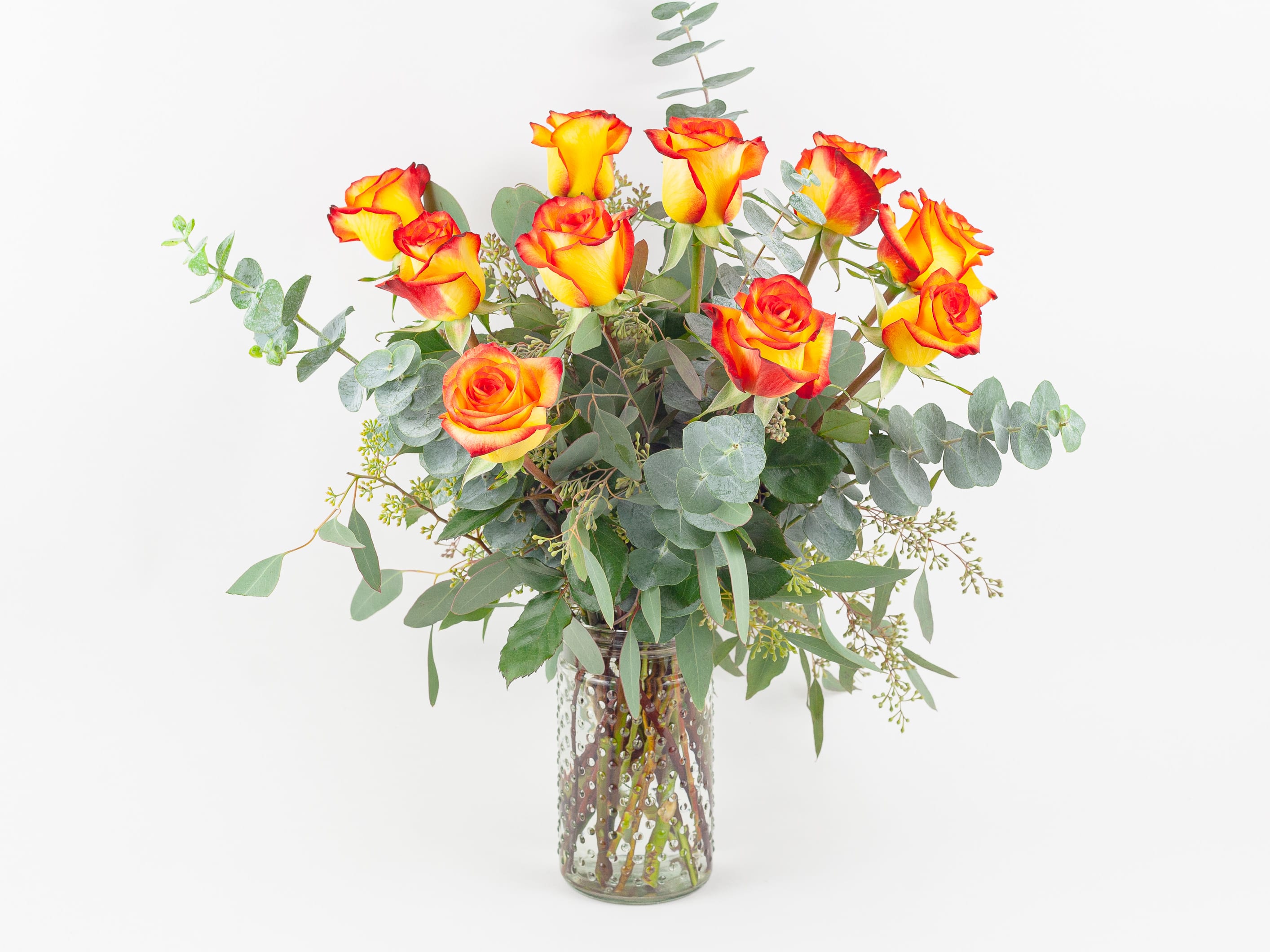 Free Spirit - LONG STEM YELLOW ORANGE ROSES IN VASE  Fresh and lush. This beautiful glass vase of 10 long stem ‘High Magic’ bi-color yellow roses with red tips is a classic-style design. Our floral designers pair these cheerful roses with a variety of silvery eucalyptus foliage for depth and contrast. The perfect vase of flowers for people who love roses and simple, understated elegance.  Send this gorgeous rose arrangement to your partner for a special anniversary or ‘I love you’ gesture any time of the year. Deliver as a get well soon or special happy birthday gift. Or give to a client or colleague to say congratulations or thank you.  Why not add a greeting card or quality handmade candle to match the occasion or personality?  Free Spirit features: ·        10 long stem ‘High Magic’ bi-color yellow-orange roses ·        Spiral eucalyptus ·        Seeded eucalyptus ·        Clear hobnail glass vase   SIZE: The STANDARD flower arrangement is approximately 18” height and 18“ width.   ALLERGY ADVICE: This design is low in pollen and has a low fragrance.   FAQ Q: What time will my flowers arrive and what if no-one is there to accept them? A: Excellent question! We’re unable to provide or guarantee specific delivery times. All our flowers are delivered anytime between 9-5pm, with exception to Sympathy designs for a funeral service. For full details around our delivery process and timings, please see our Terms and Conditions. Q: What days do you deliver flowers? A: All our flowers are available for San Francisco and Daly City delivery seven days a week, between 9am-5pm. Q: May I order for the same day delivery? A: Yes, same day deliveries are available if you place an order before 1pm. Q: May I request to change the design a bit? A: Yes, please make a note in the SPECIAL INSTRUCTION box when you place your online order. We will do our best to follow them. Q: Will my flowers look exactly as what is pictured? A: Depending on the season, colors or shades may vary. Sometimes we need to substitute flowers due to seasonal availability, but they’re always substituted for the same or greater value.   Ready to bring floral beauty into someone’s world with our vase of yellow-orange roses? Order this gift online now or give us a call on (415) 752-2060 if you have a question or special request. 