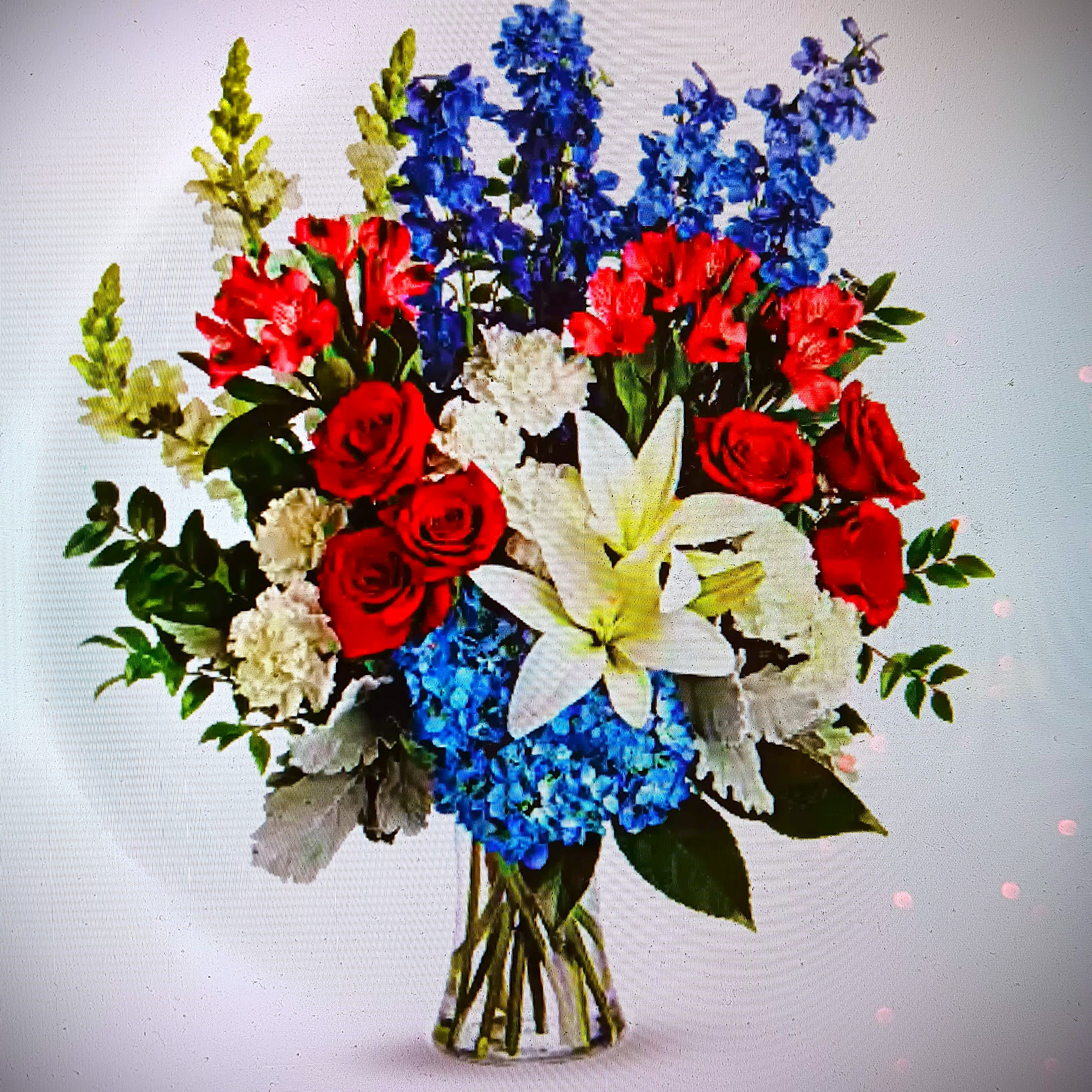 Colorful Tribute - Fresh floral arrangement of red, white, and blue blooms with roses, lilies, hydrangea, alstroemeria, carnations, and other seasonal flowers, in a clear glass vase. It's a colorful tribute for someone special, both perfectly patriotic and gorgeous. Good for sympathy as well as for so many other occasions. We deliver! 