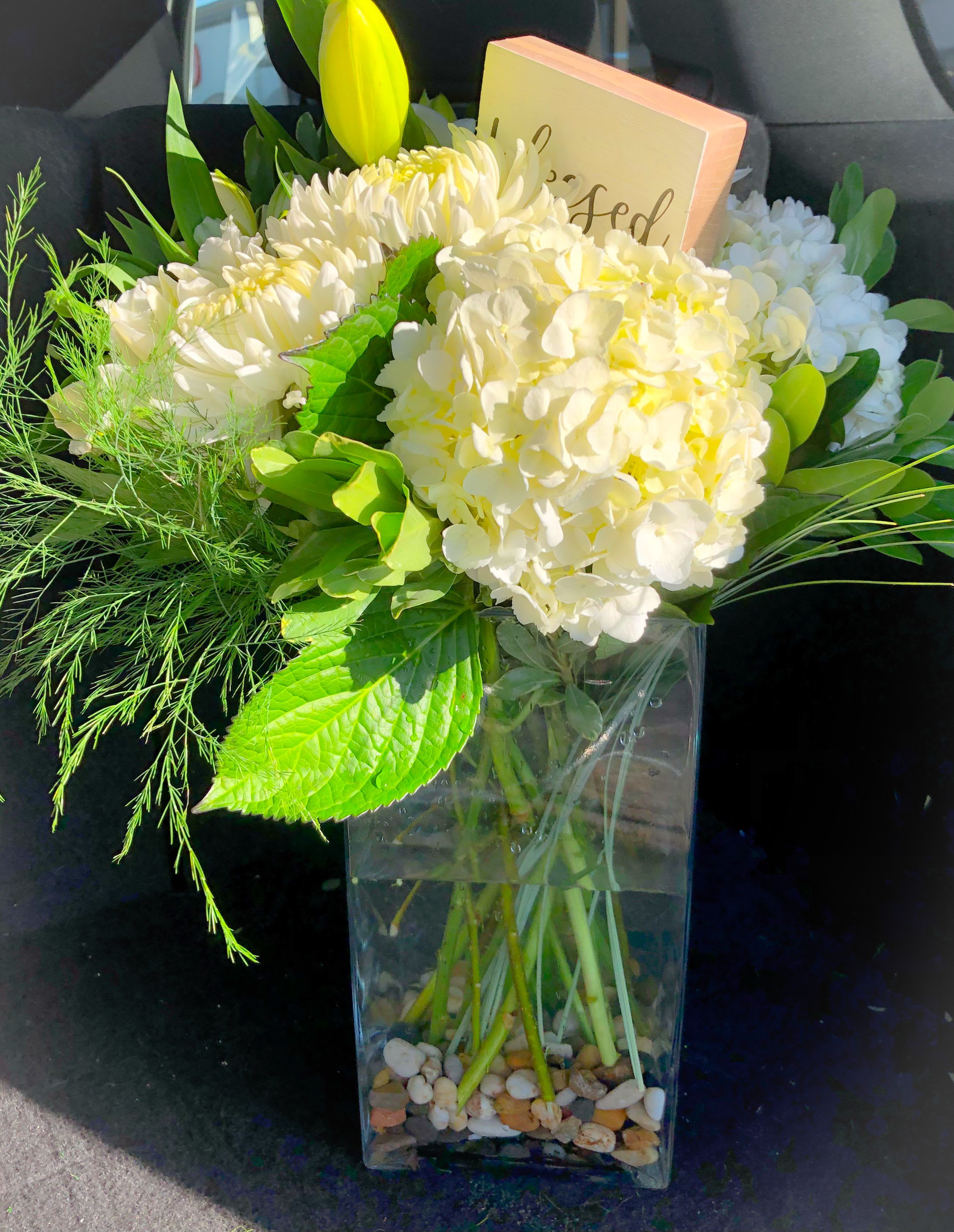 BLESSED - WHITE HYDRANGEA, WHITE ORIENTAL LILIES AND WHITE ROSES, WITH GREENS AND A SMALL WOODEN SIGN THAT READS &quot;BLESSED&quot;