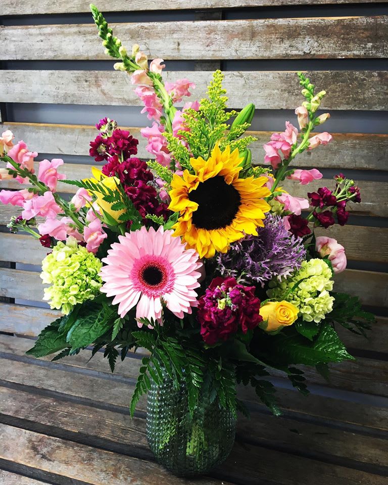 Pinks, greens  and yellows in clear gathering vase  - Clear glass gathering vase filled with designer's choice assortment of pink, yellow and green seasonal flowers . 