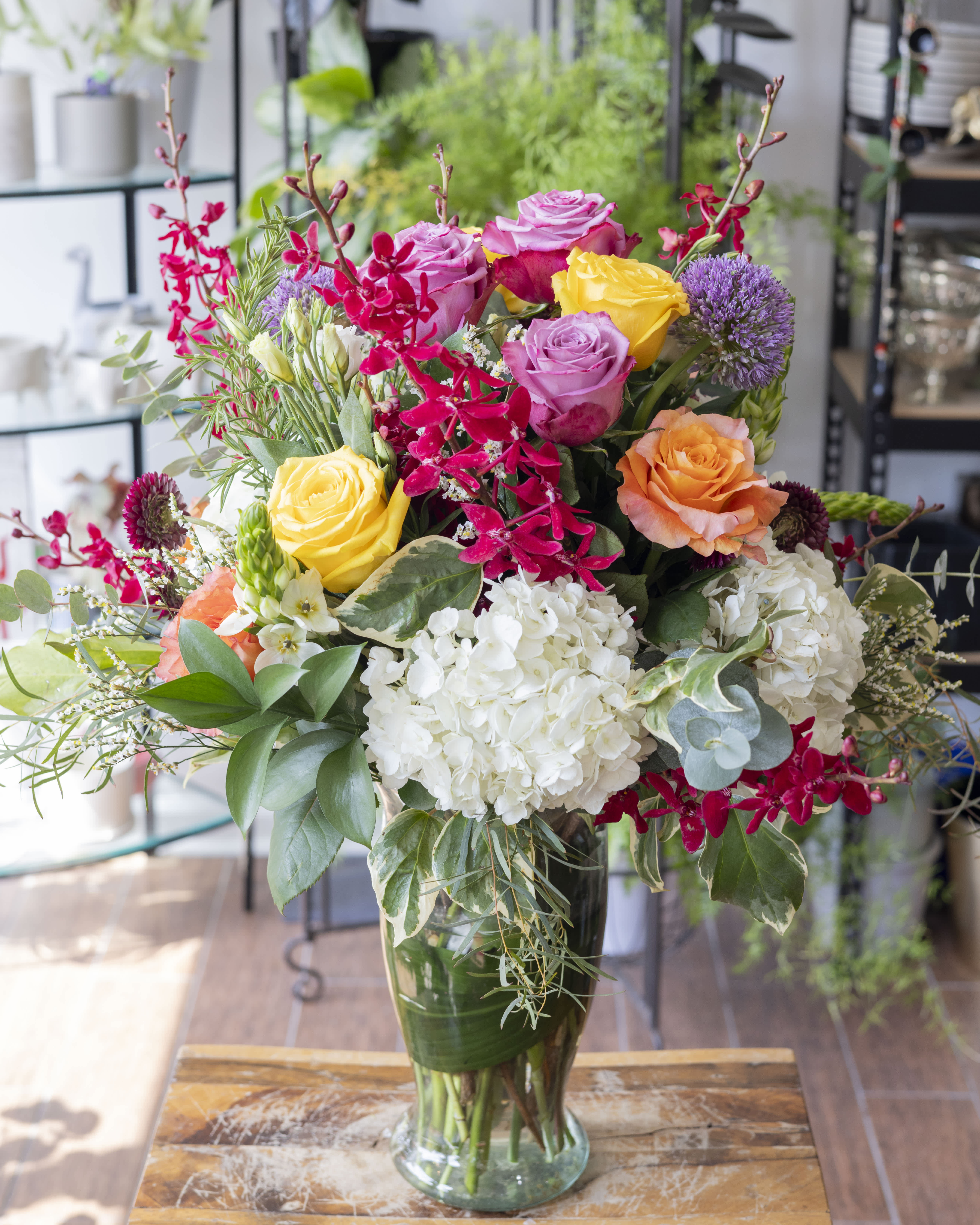 Dinah - Bright and colorful tall arrangement with a variety of flowers, arranged in a clear glass vase.
