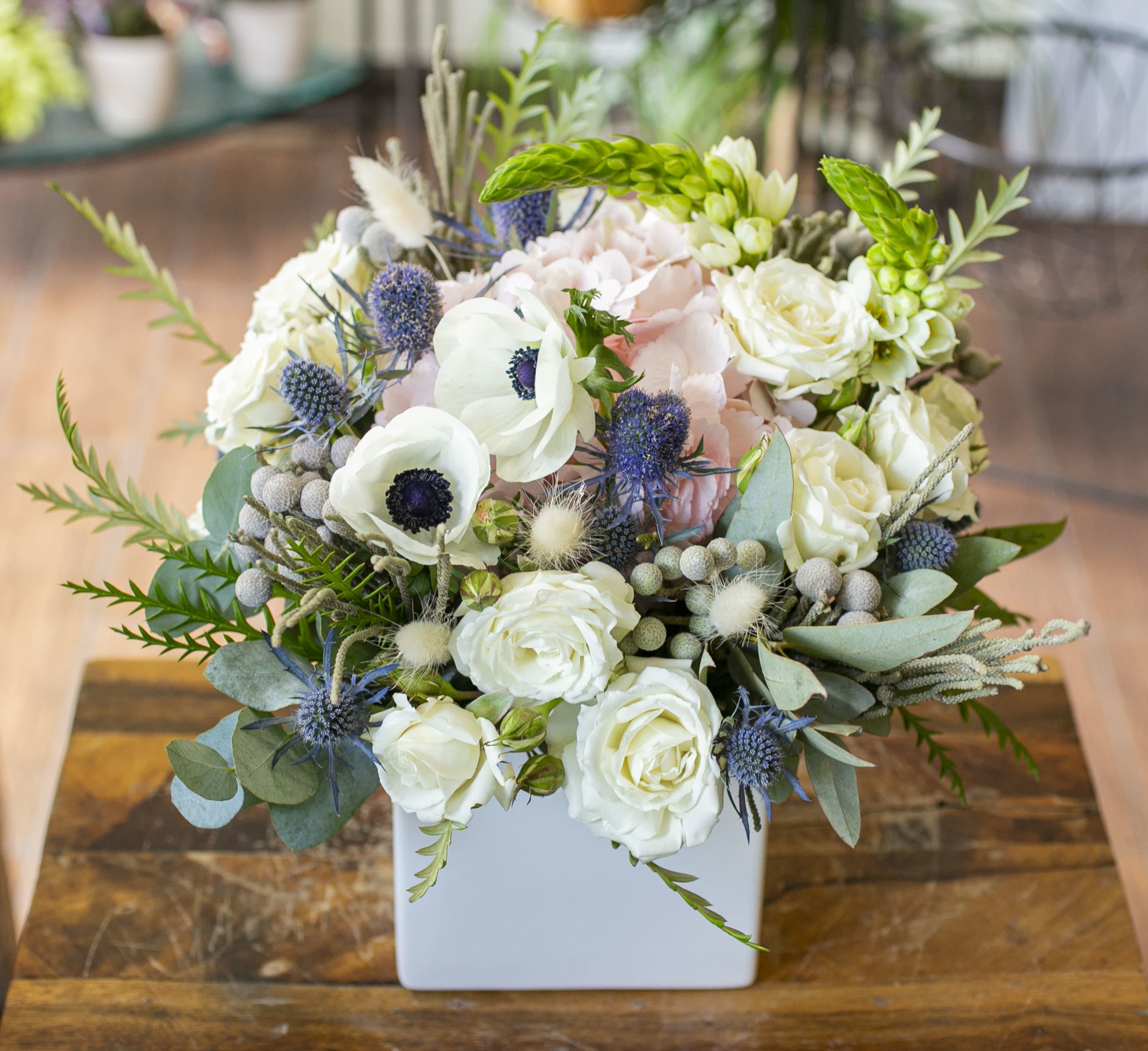 Antoinette - Pale pink and white flowers arranged in a white ceramic container. 