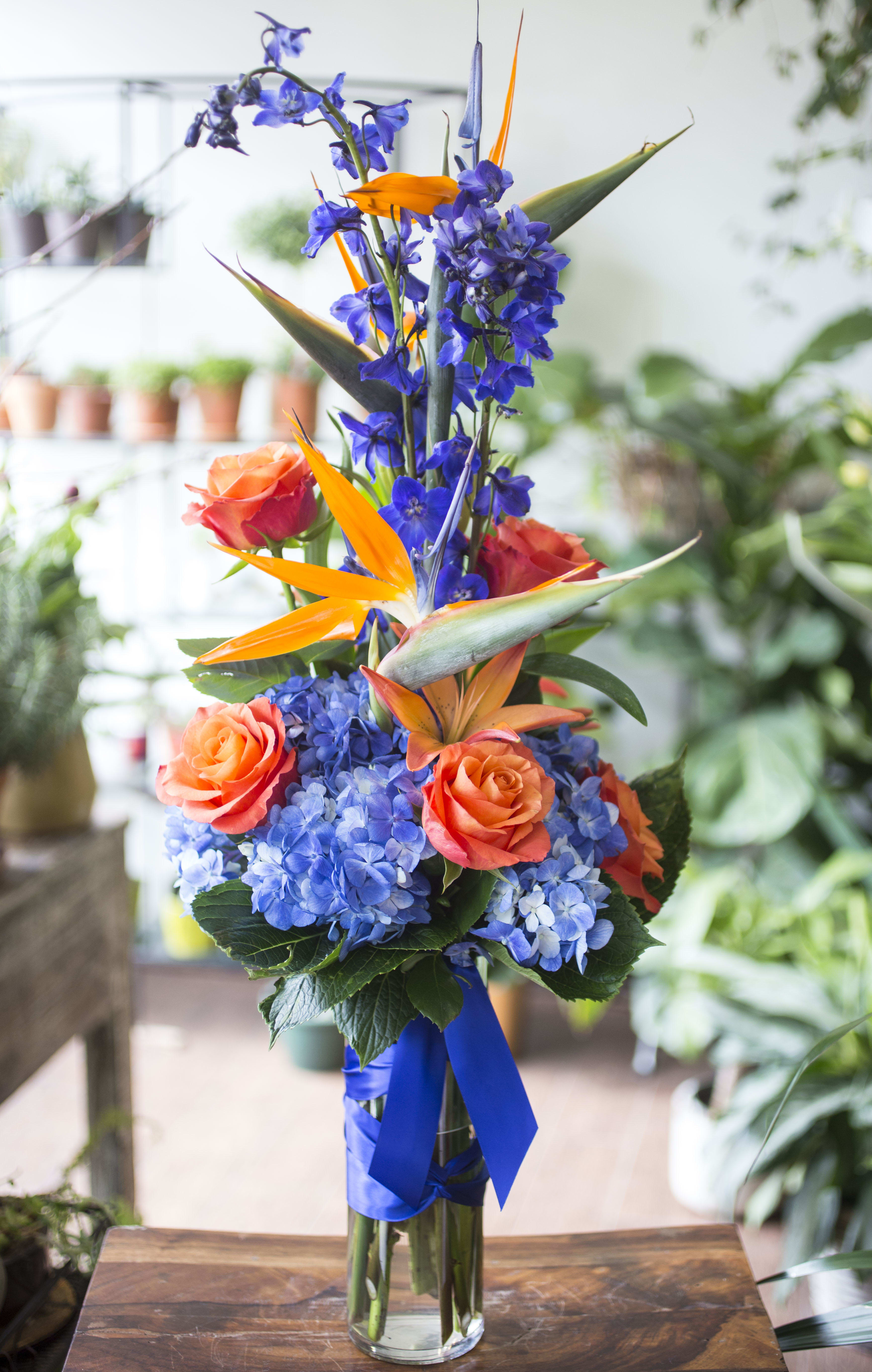 Bobbi - Blue and orange with Birds of Paradise, Hydrangeas, Delphinium and Roses arranged in a cylinder glass vase.