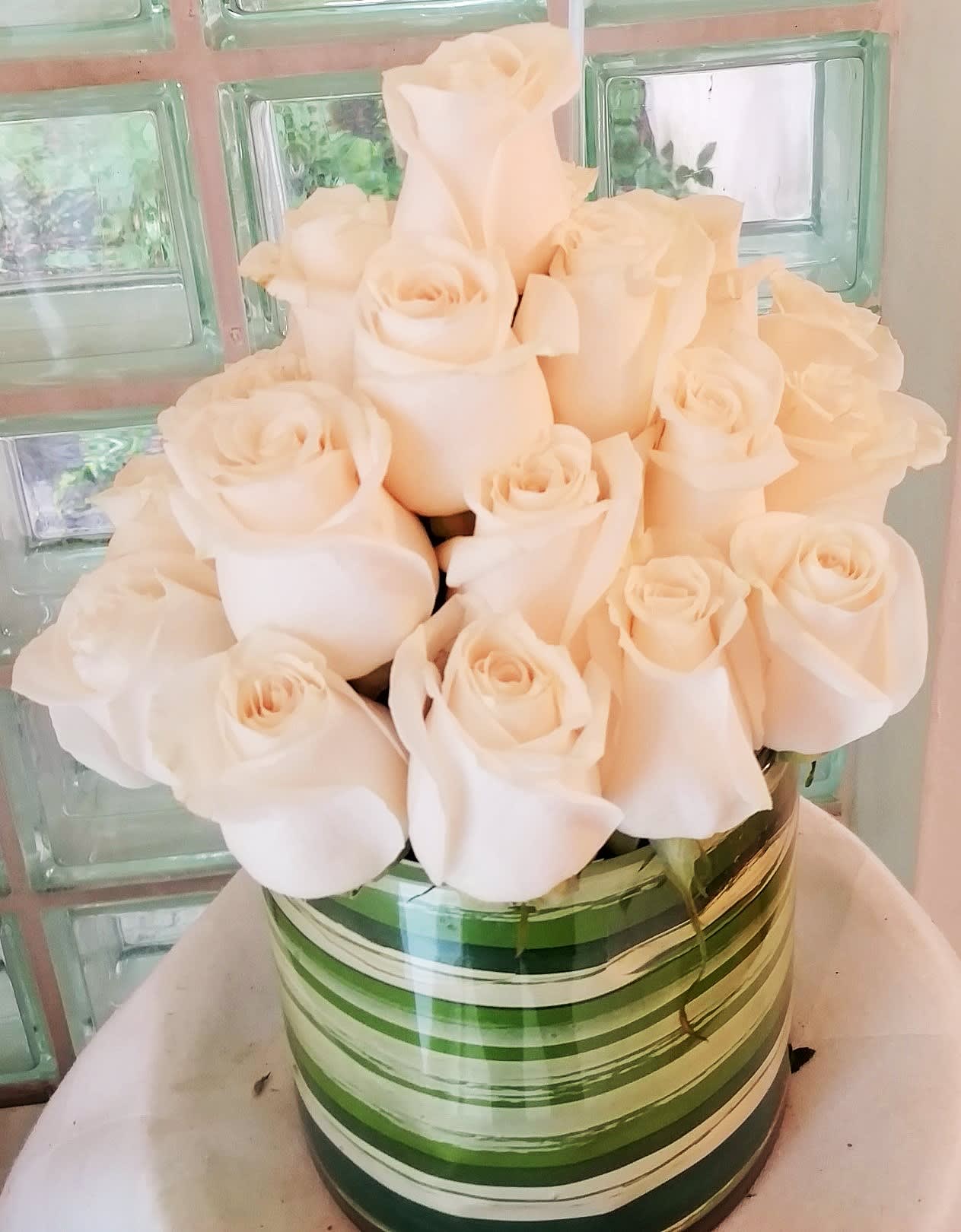 White Roses in a Contemporary Design - We've cut the roses extra short and set them in a low cylinder for you to admire.