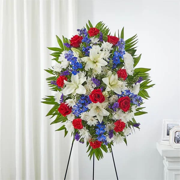 Cherished Service Standing Spray - A red, white and blue expression of love and service to honor an incredible life.  The scale of the arrangement should determine the type of substitution acceptable, but the substitution must be of equal or greater value and must maintain the style and color harmony of the original order.