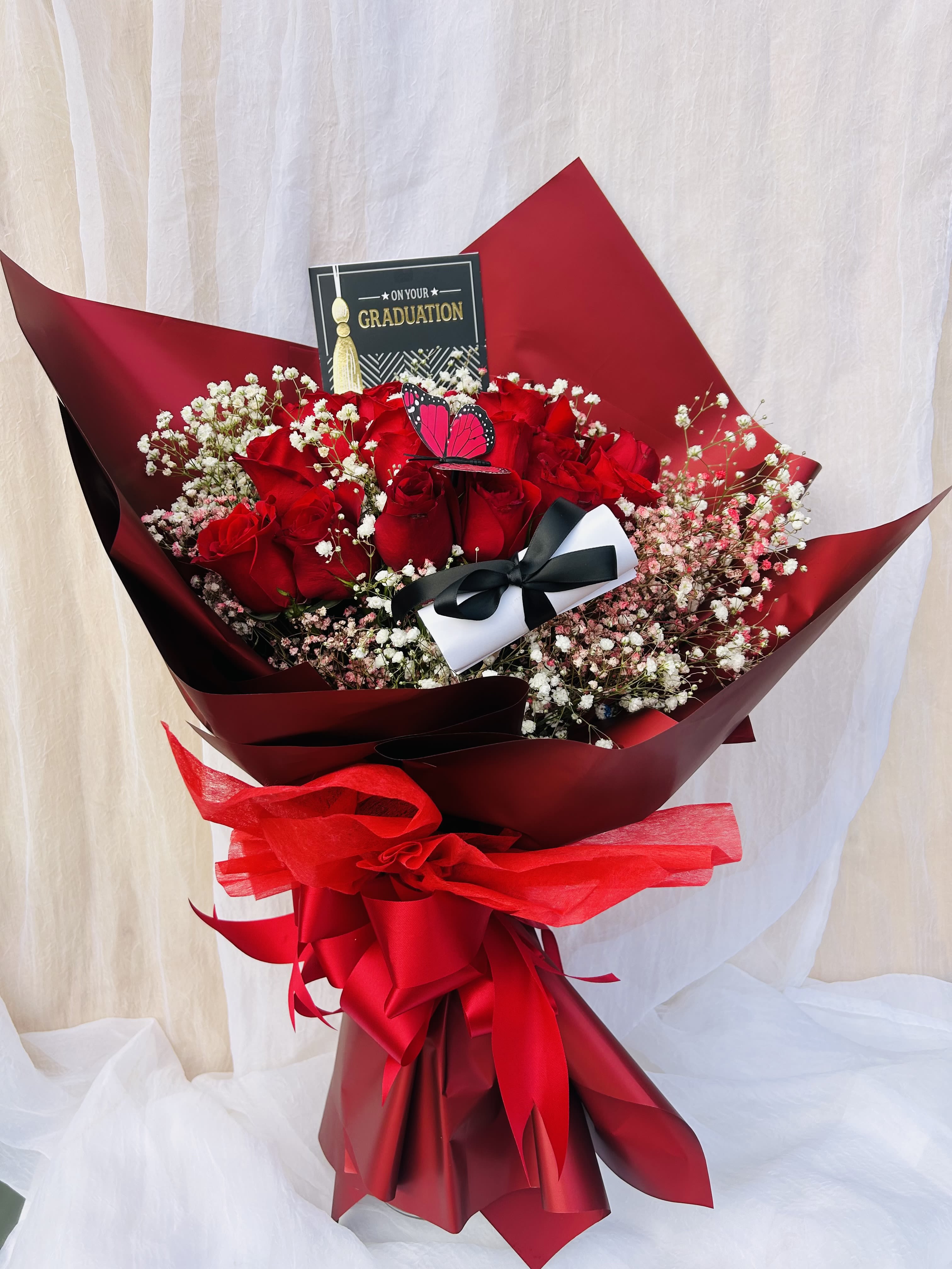 For the Grad! - Beautiful wrapped bouquet featuring red roses and baby breathe. 