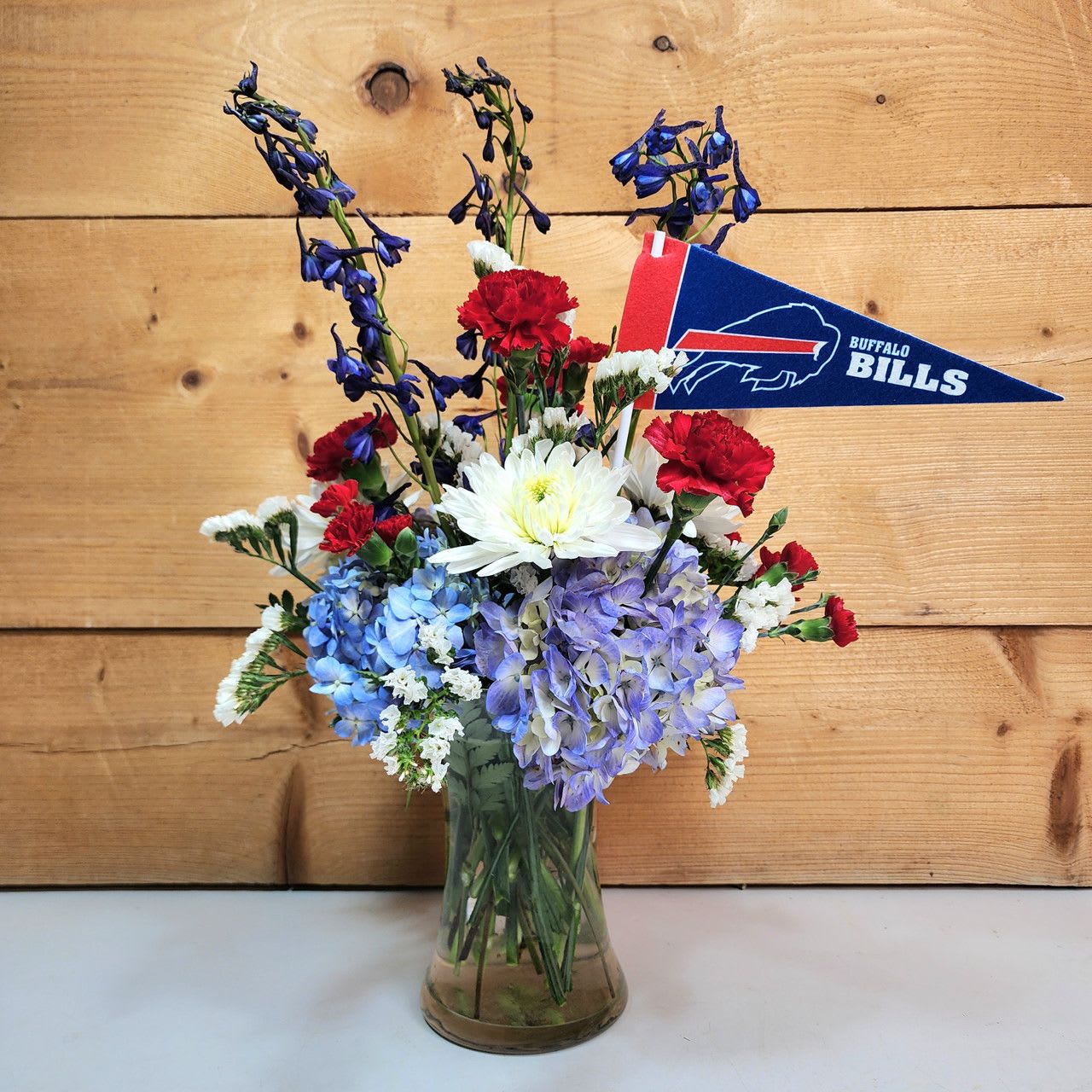 Go Bills Bouquet - Go Bills Bouquet by Savilles Country Florist featuring red, white, and blue fresh cut blooms, and a Buffalo Bills pennant,  presented in a glass vase.  Approx 22&quot; H x 18&quot; W  PLEASE NOTE: Some flowers, vases and other products pictured are subject to availability, and may be substituted for a similar item if unavailable according to our substitution policy.