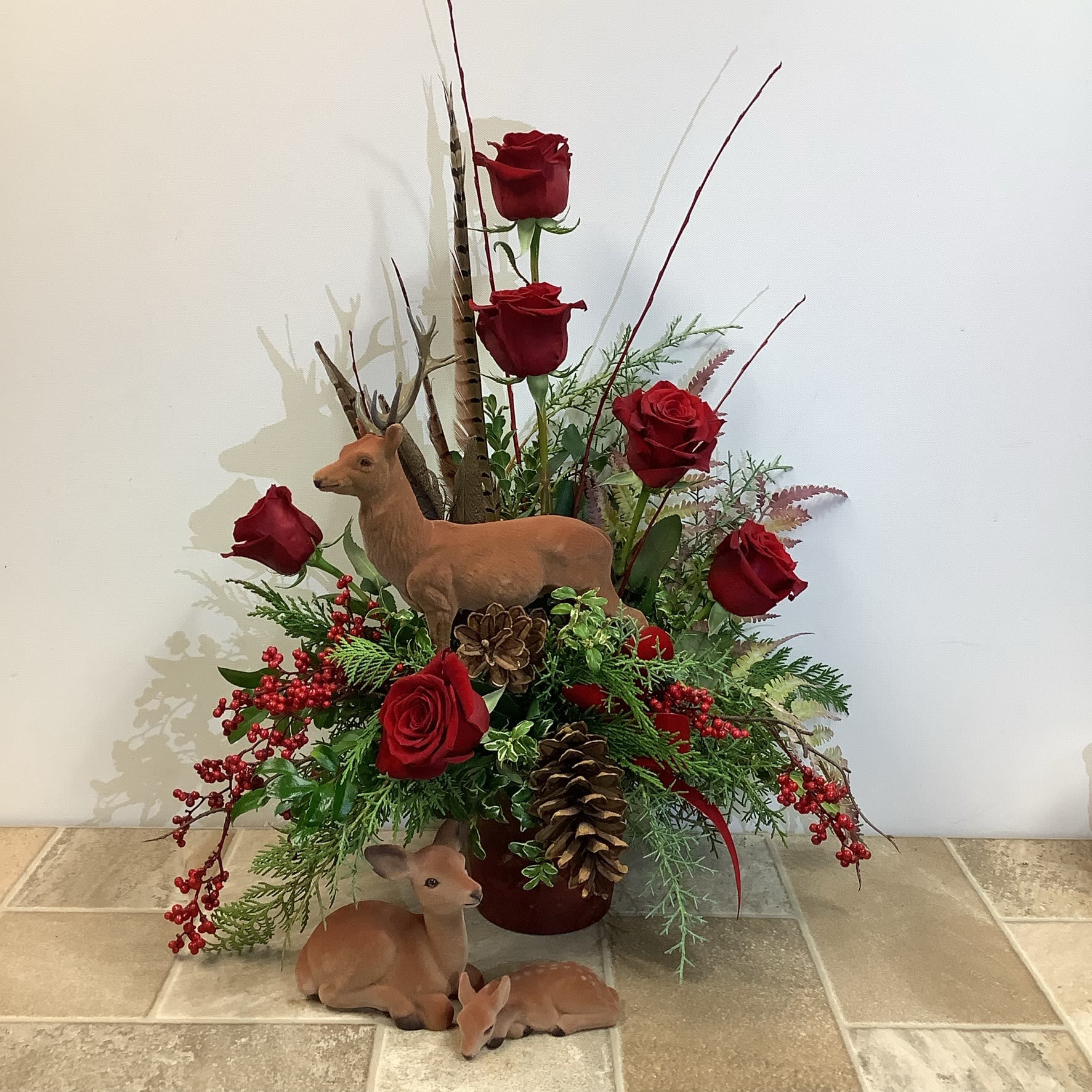 Oh Deer! Oh Deer! - "Oh Deer!" is a rustic, woodland arrangement certain to please outdoor lovers. A set of deer figurines are included, along with fresh evergreens, six red roses, clusters of berries, a pine cone, and pheasant feathers, all set in a metal container. Perfect for memorial, autumn or winter occasions. Primary flower: rose