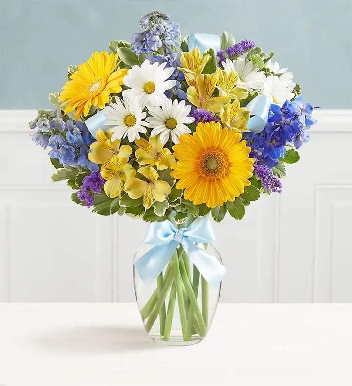 Sweet Baby Boy™ Arrangement - A precious baby boy has arrived, and you couldn’t be happier! Surprise the proud new parents with our cheery bouquet. Designed in a glass vase finished with blue ribbon accents, it’s a sweet way to welcome their little bundle of joy into the world.