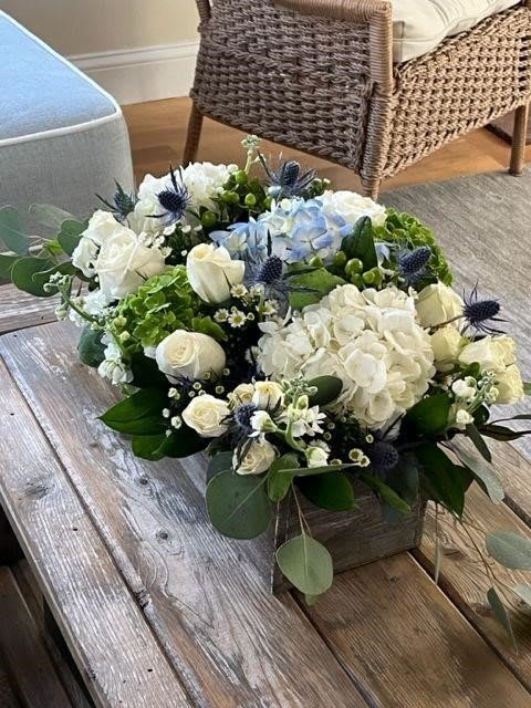 COASTAL ELEGANCE COASTAL ELEGANCE - (PREMIUM Shown) Long and Low Rectangular Whitewash Wooden Box Arrangement Measuring: 3 ½” H x 11 ¼ “ L x 4” W, Filled with White, Blue and Green Hydrangea, Blue Thistle, White Roses, White Clustered Roses, Green Hypericum Berry, Premium Filler Flowers, Lemonleaf and Eucalyptus Silver Dollar