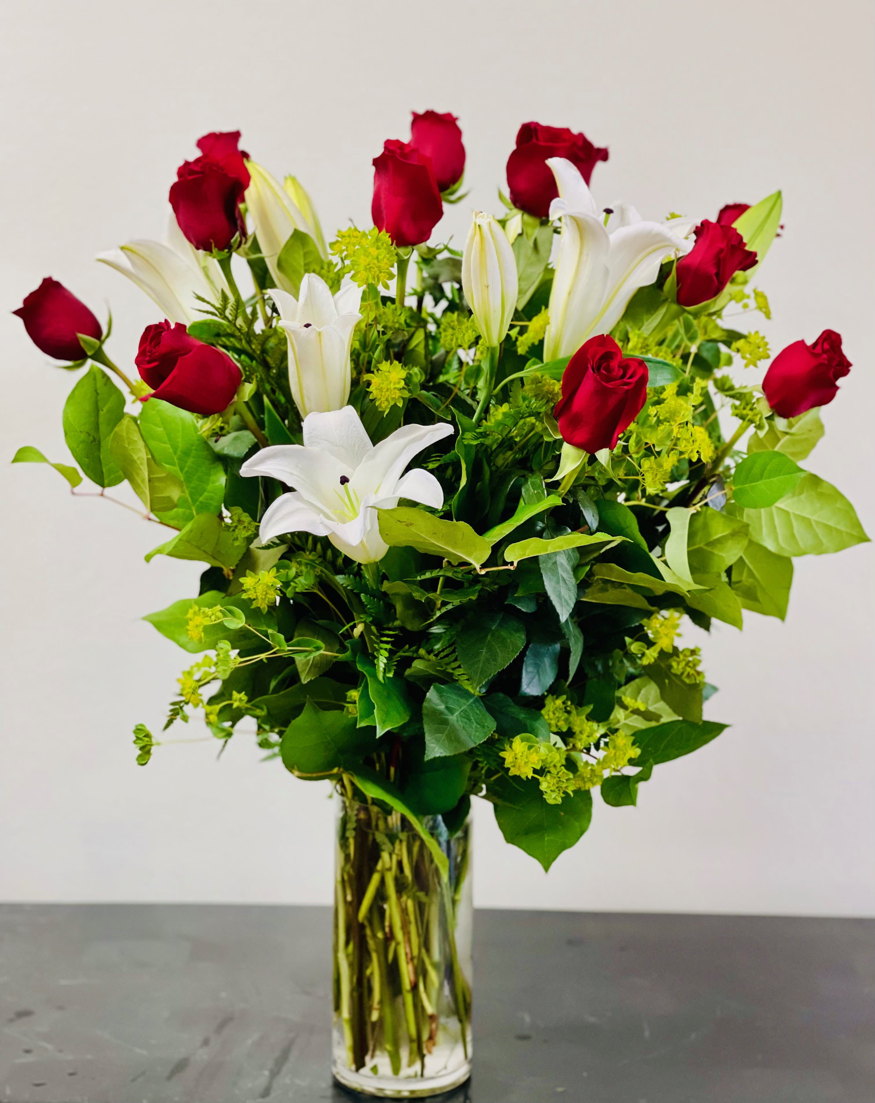 BF-M8 Elegant Love: 12 Red Roses & White Lilies in Vase BF-M8 Elegant Love: 12 Red Roses & White Lilies in Vase - Celebrate love with refined beauty in our Elegant Love arrangement. Featuring 12 premium red roses paired with stunning white lilies, this glass vase arrangement is a timeless expression of passion and grace. The deep red roses symbolize heartfelt affection, while the elegant white lilies bring a sense of purity and calm. Expertly arranged in a clear glass vase, this bouquet makes a perfect gift for anniversaries, romantic occasions, or simply to say "I love you" in the most elegant way.