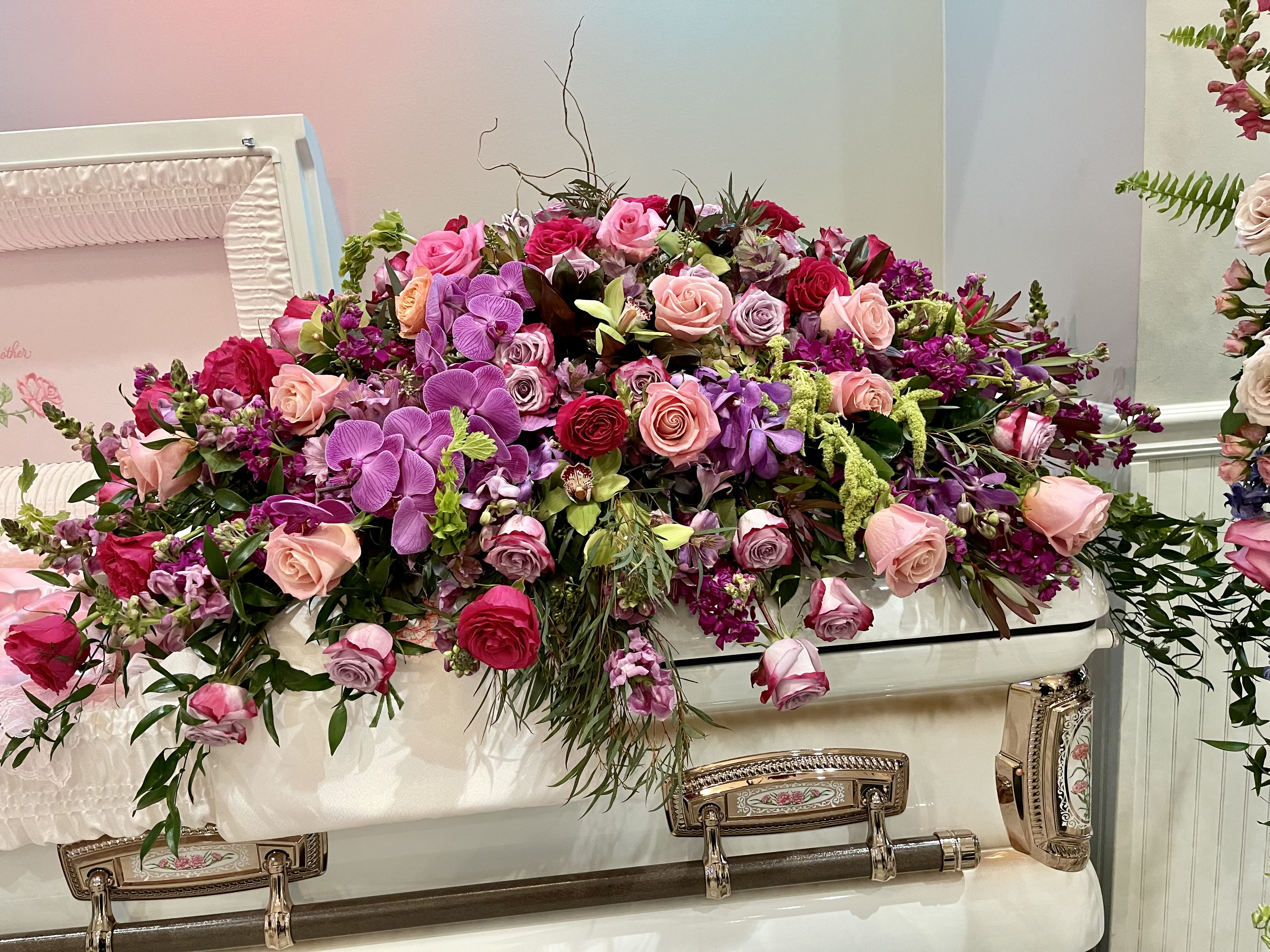 Timeless Treasure - A bold and beautiful tribute, Timeless Treasure is a jewel-toned casket spray designed to honor a life lived with vibrance, strength, and grace. This luxurious arrangement features a stunning mix of roses, stock, snapdragons, kale, and Bells of Ireland, alongside exotic Cymbidium and Mokara orchids, Phalaenopsis blooms, curly willow, ruscus, and lush seasonal greenery.  Carefully crafted by Julia’s Floral, Timeless Treasure offers a meaningful expression of love and remembrance, ideal for services that call for something truly distinctive. Available by advance order for delivery in the Dallas area.