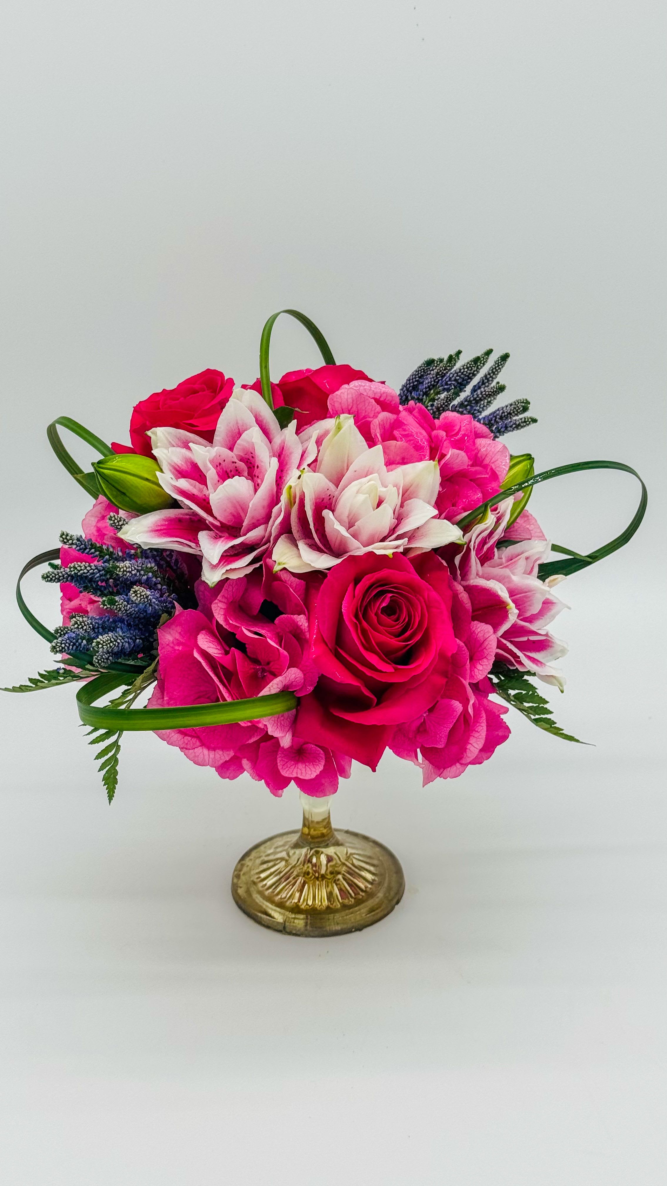 Elegant pink Elegant pink - A stunning floral display featuring vibrant pink and hot pink roses, delicate premium hydrangeas, and elegant double Stargazer lilies, all beautifully arranged in a golden glass container. This arrangement exudes sophistication and charm, perfect for brightening any space or celebrating a special occasion."