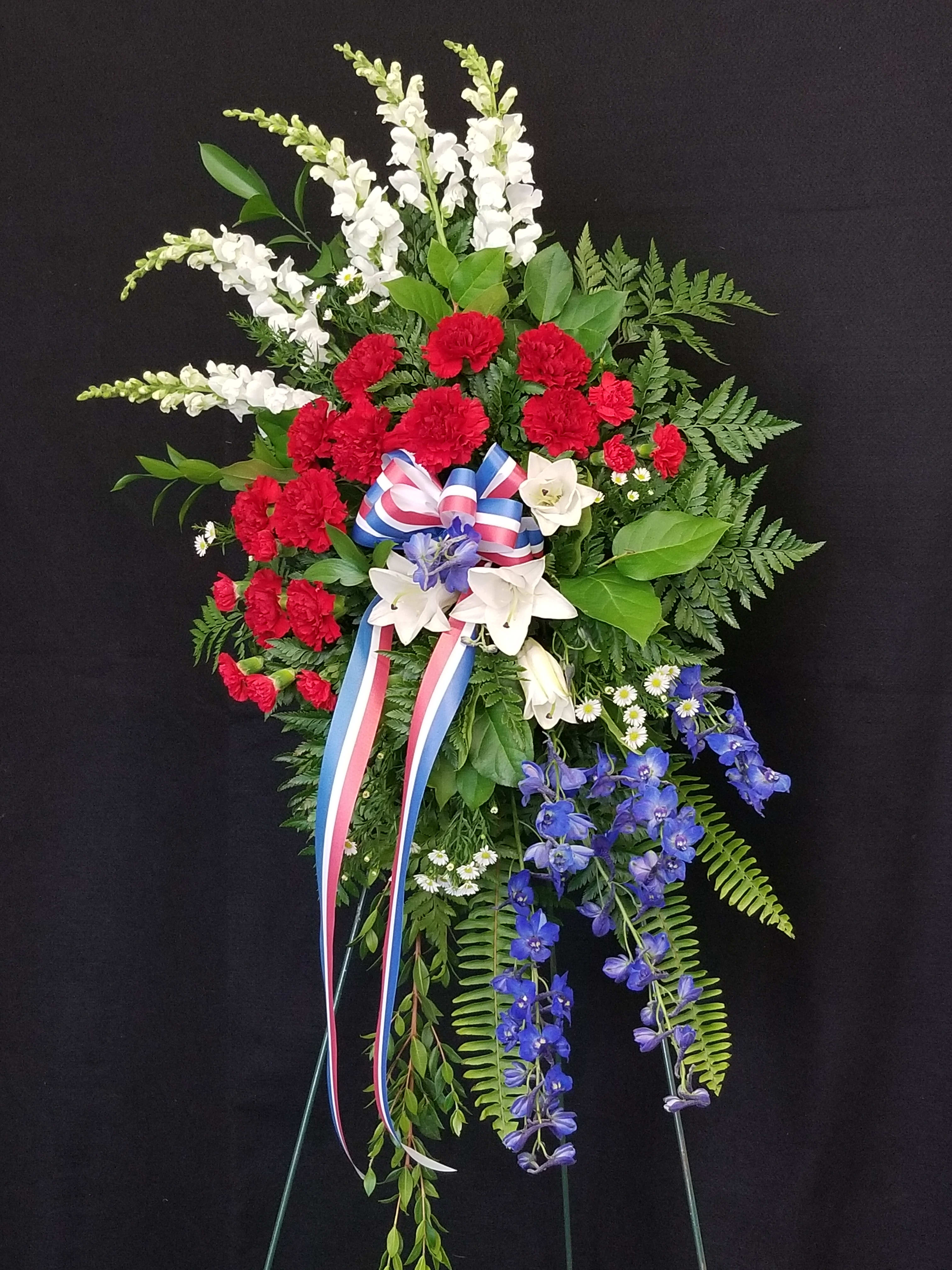 Red, White, and Blue Spray Red, White, and Blue Spray - a dynamic spray of snapdragons, carnations, lilies, delphinium, and assorted greens with a matching ribbon
