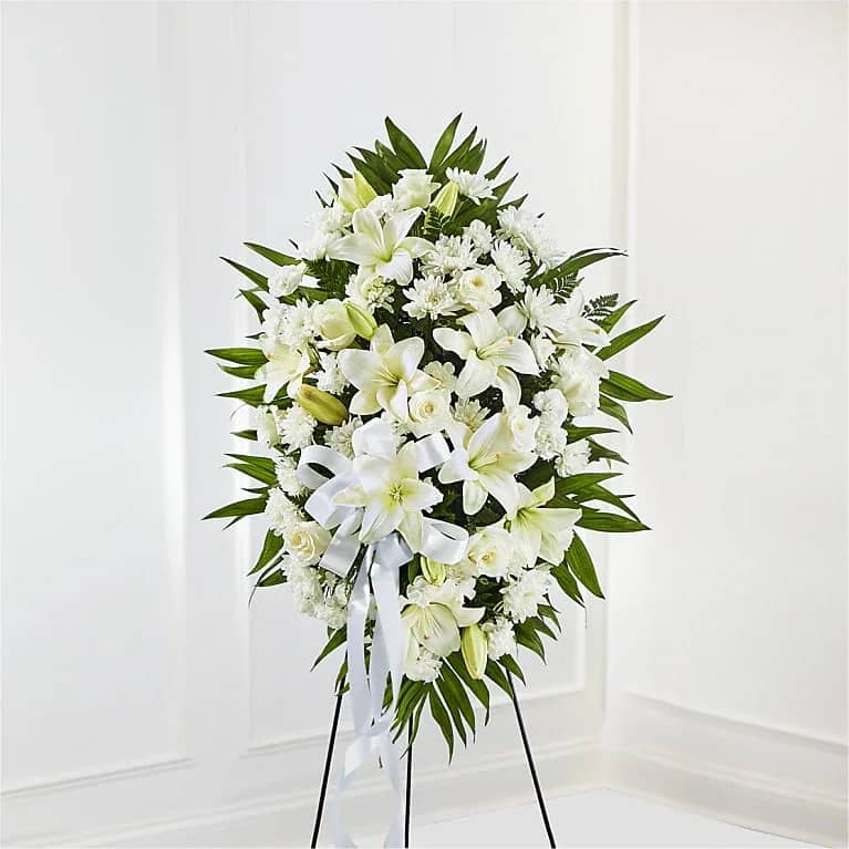 Exquisite Tribute Standing Spray - The Exquisite Tribute Standing Spray is an elegant display of sweet serenity. White roses, Asiatic lilies, chrysanthemums and mini carnations are artfully arranged amongst emerald palm fronds and lush greens. Accented by white satin ribbon and standing on a wire easel, this standing spray is an outstanding way to honor the life of your loved one. Carnation Lily Rose