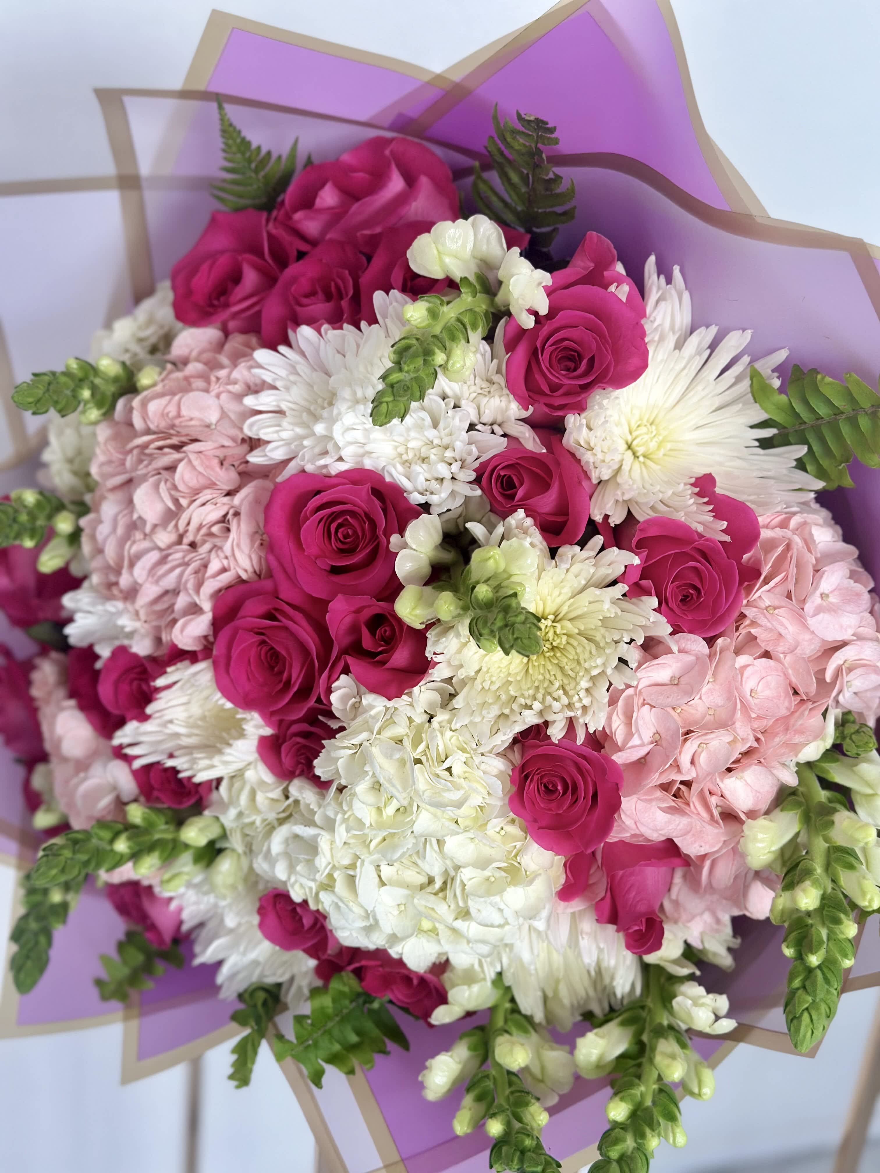 Fairy Floral Bouquet - Imagine a bouquet straight out of a fairy tale, bursting with vibrant hues and delicate blooms. This enchanting arrangement features a mesmerizing combination of hot pink roses, pure white chrysanthemums, lush clusters of hydrangeas, and snapdragons.  