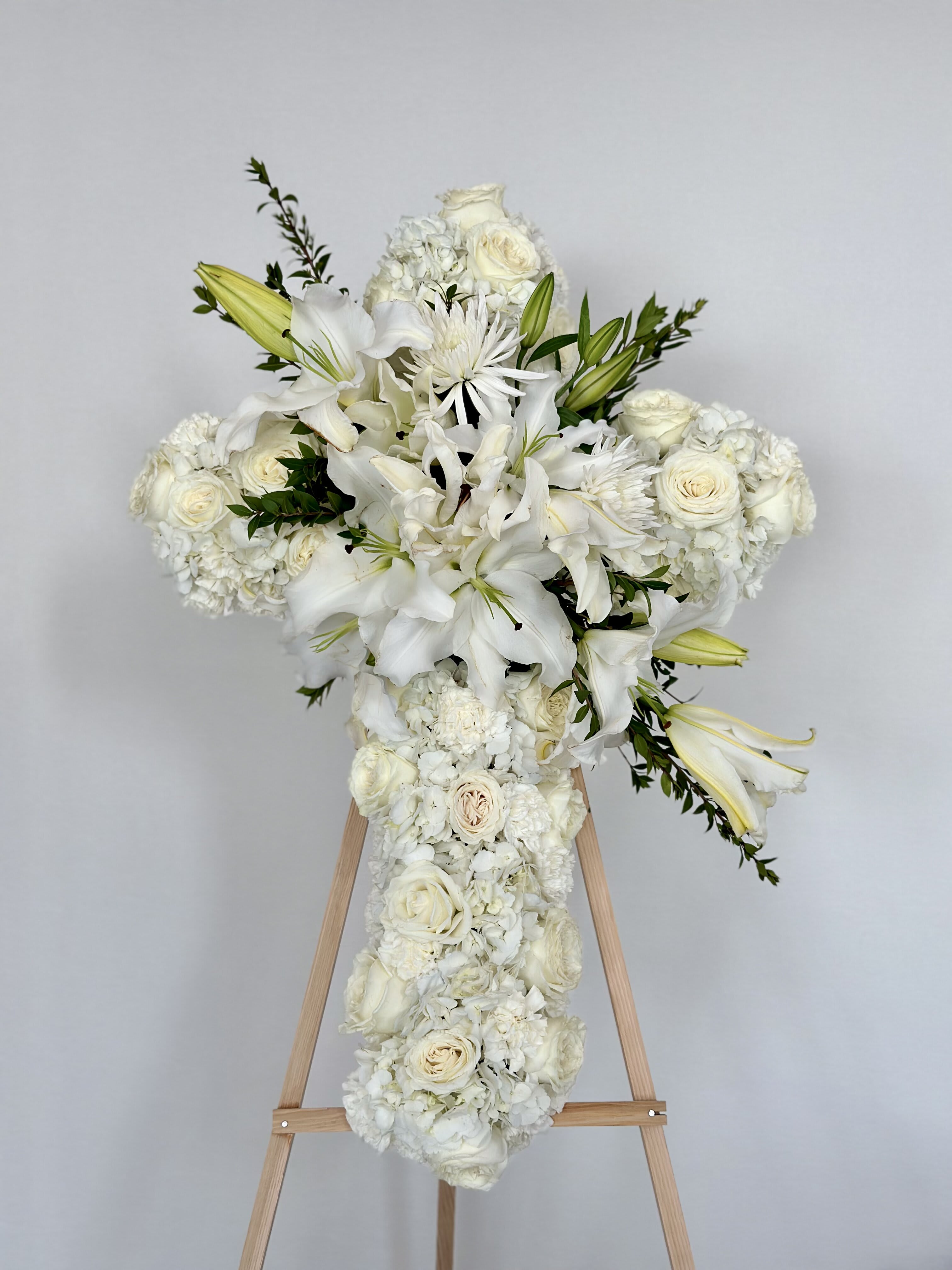Serenity Heart Funeral Cross Wreath Serenity Heart Funeral Cross Wreath - This funeral cross is meticulously adorned with a harmonious blend of white roses, hydrangeas, lillies, carnations, and chrysanthemums. Each flower carries its own poignant symbolism, collectively honoring the life and memory of a cherished individual.