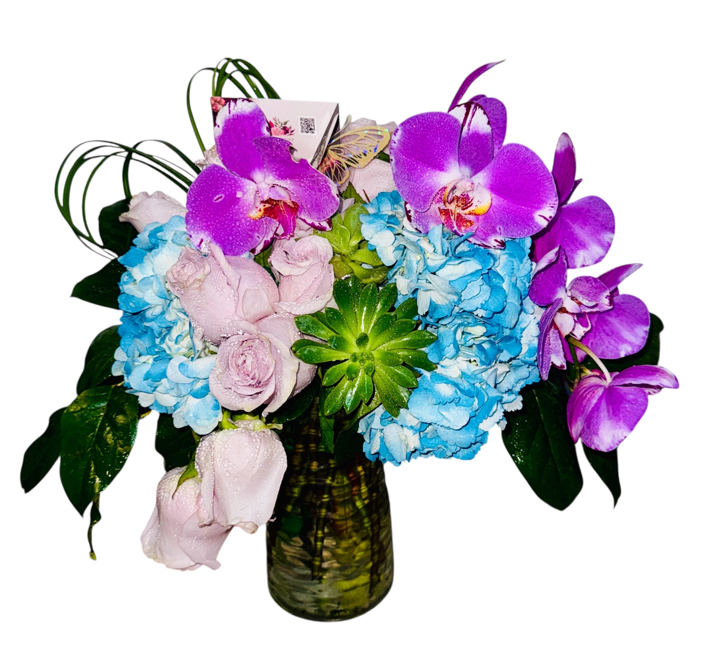 Orchid Reverie - This lush arrangement unfolds like a dreamy garden in bloom, featuring the exotic allure of purple orchids, tender blush roses, and tranquil blue hydrangeas. Nestled among verdant succulents and airy grasses, the bouquet creates a balance between refinement and natural whimsy. Presented in a clear glass vase with a modern touch—a discreet QR code card—it hints at a story waiting to be discovered. *Orchid Reverie* evokes serenity, creativity, and graceful curiosity 