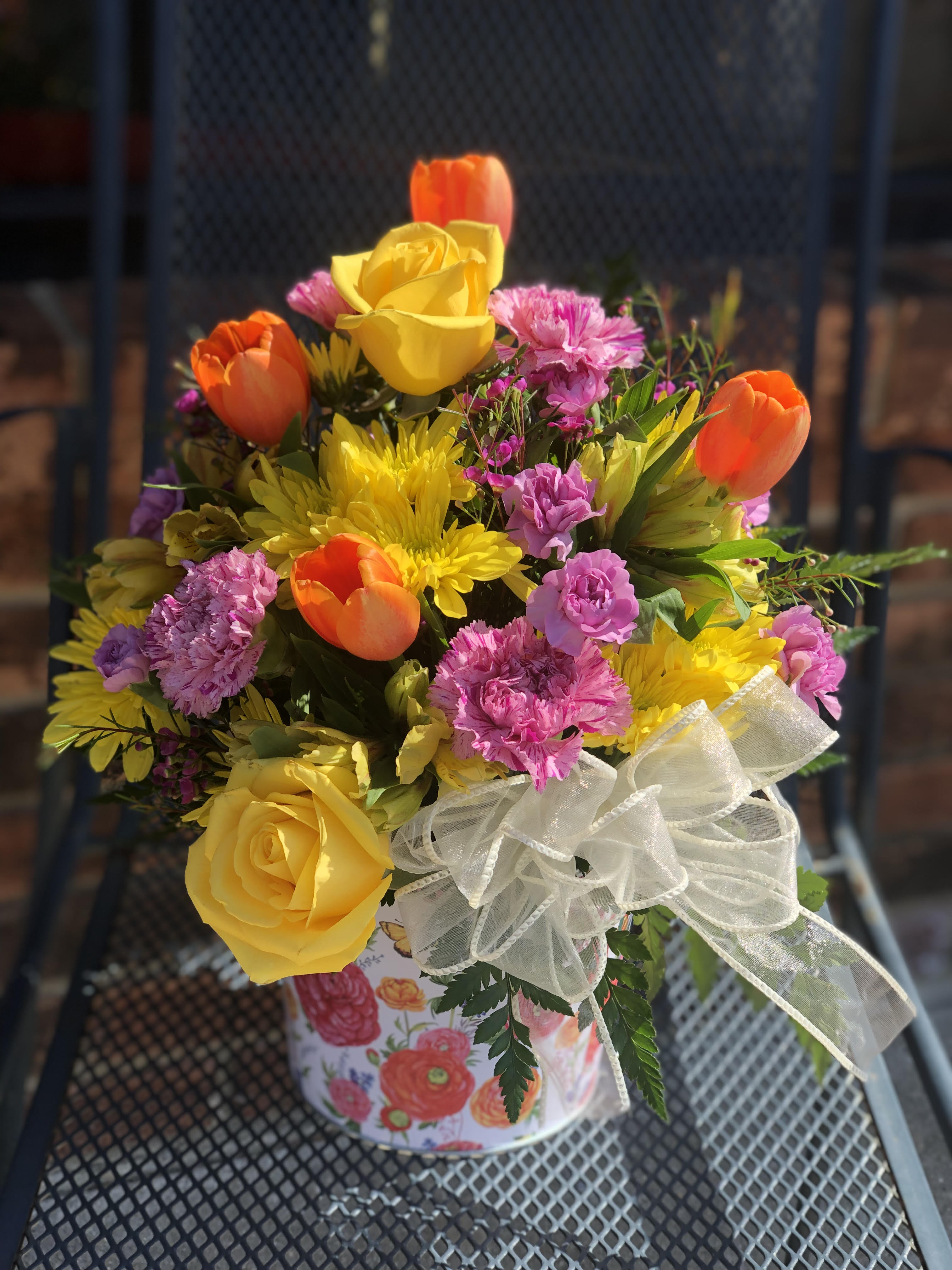 Buckets Full Of Poises - Celebrate the joy of the new season with this springtastic bouquet! Fresh and colorful blooms, of brght tulips, mums roses and carns - fill this colorful tin container (while supplies last)  - colors may vary CONTAINER IS OUT OF STOCK *ARRANGEMENT IS ONE-SIDED*