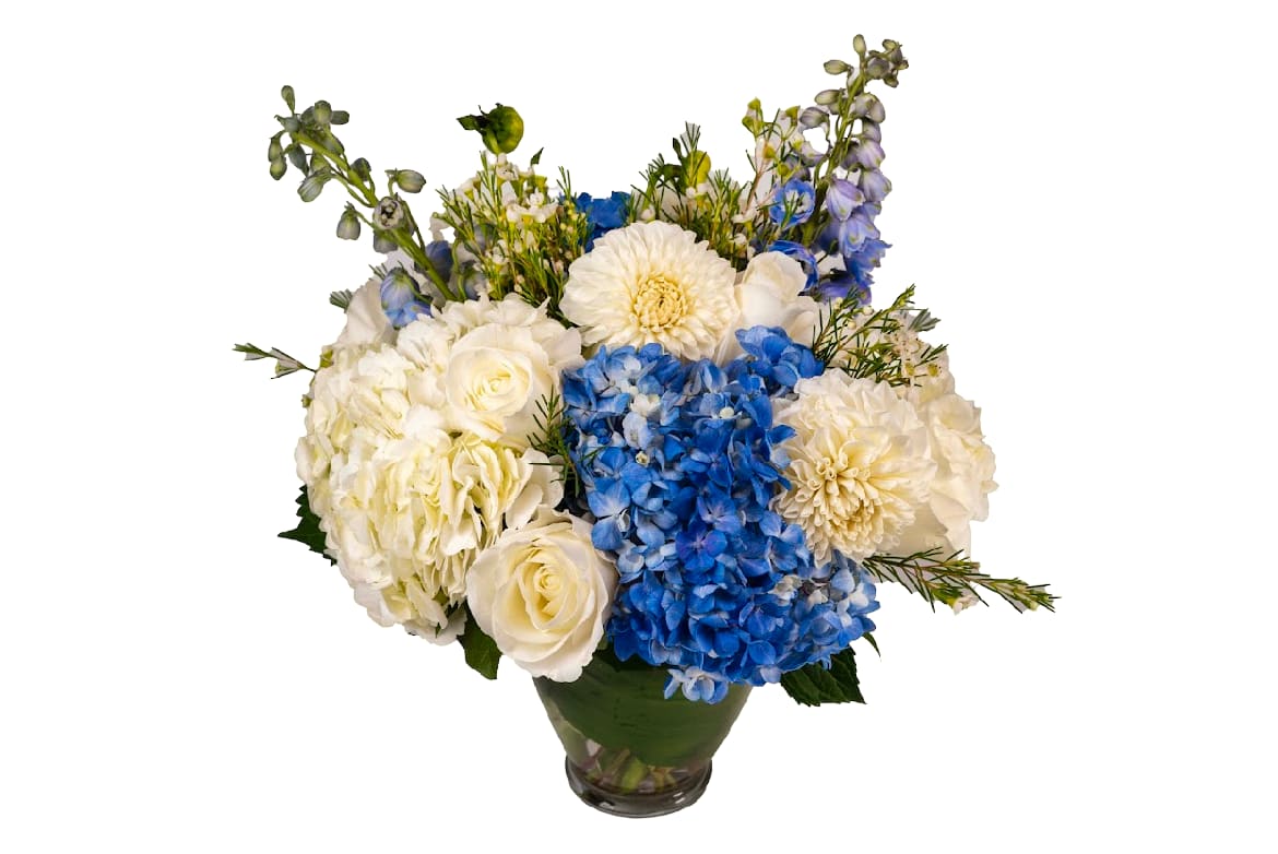 Classic Blue &amp; White - Blue hydrangeas, dahlias, roses, blue delphinium and more designed in a leaf wrapped glass vase. As Shown In Photo